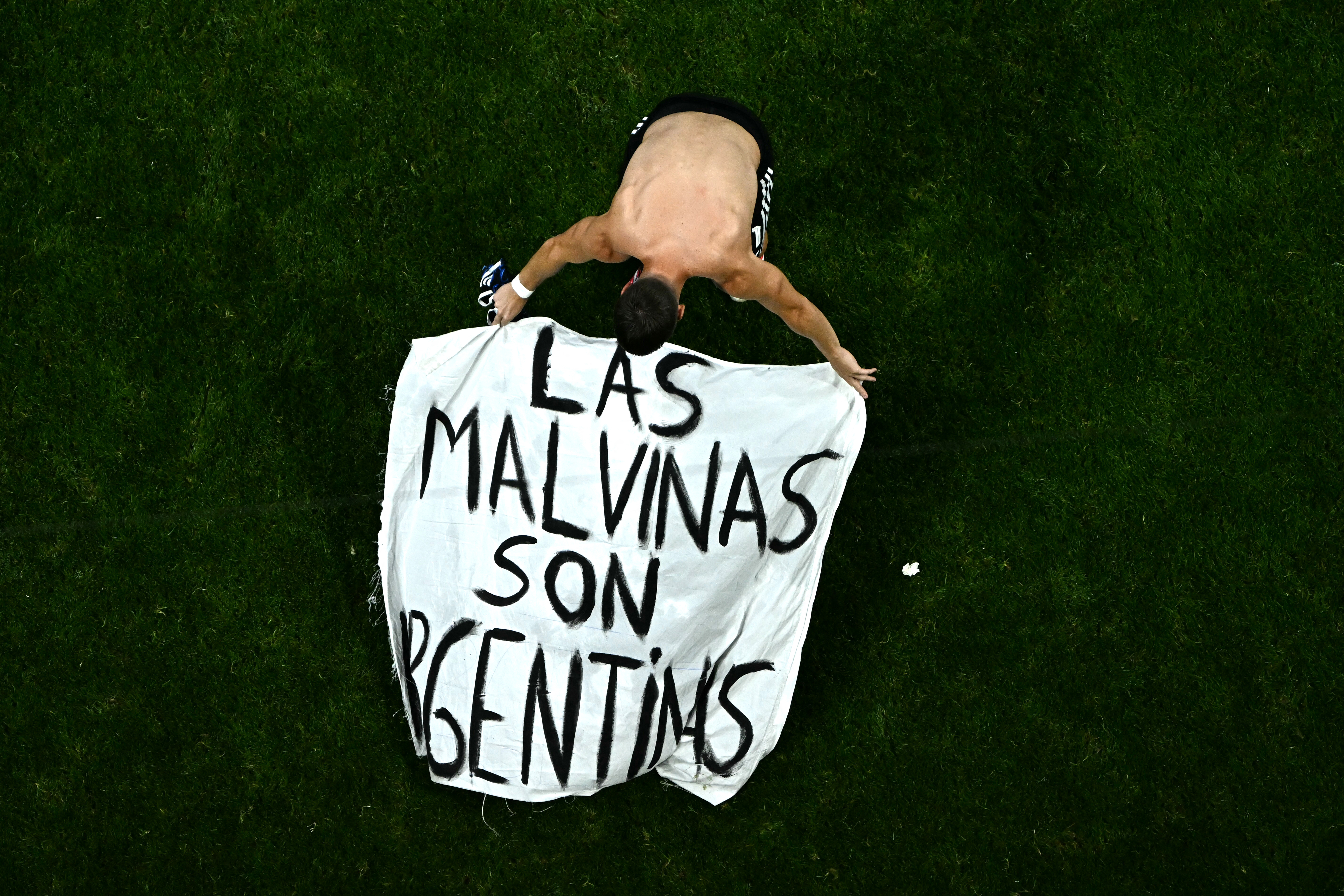 TOPSHOT - Argentina's midfielder #11 Giovani Lo Celso adjusts a banner reading "The Malvinas (Falkland Islands) belong to Argentina," after winning the 2026 World Cup football tournament semi-final match between England and Argentina at the Atlanta Stadium in Atlanta on July 15, 2026.
