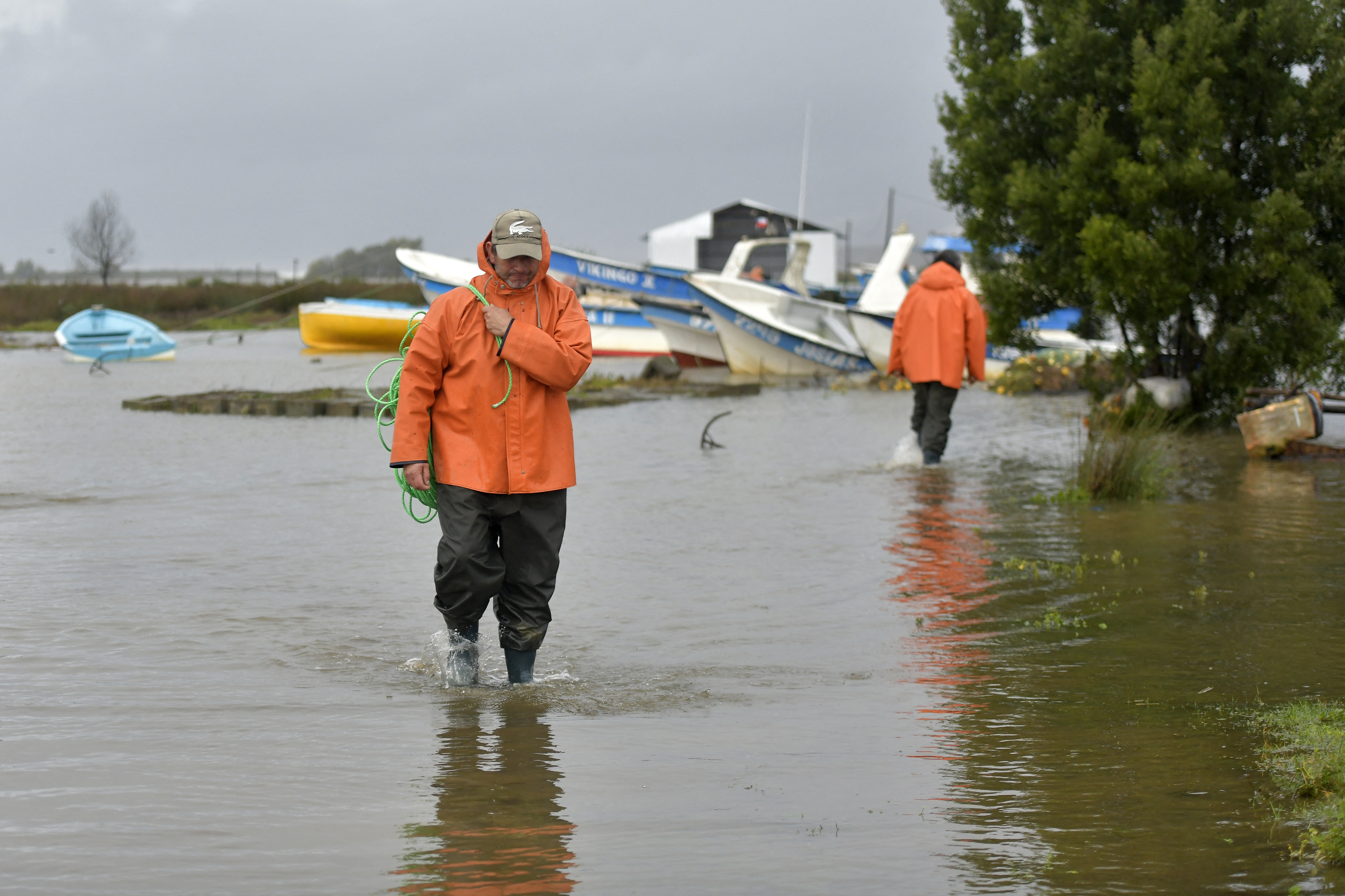 Fishermen wade through a flooded area in the coastal city of Arauco, BioBio region, province of Arauco, Chile on July 16, 2026, following strong storms hitting the region.