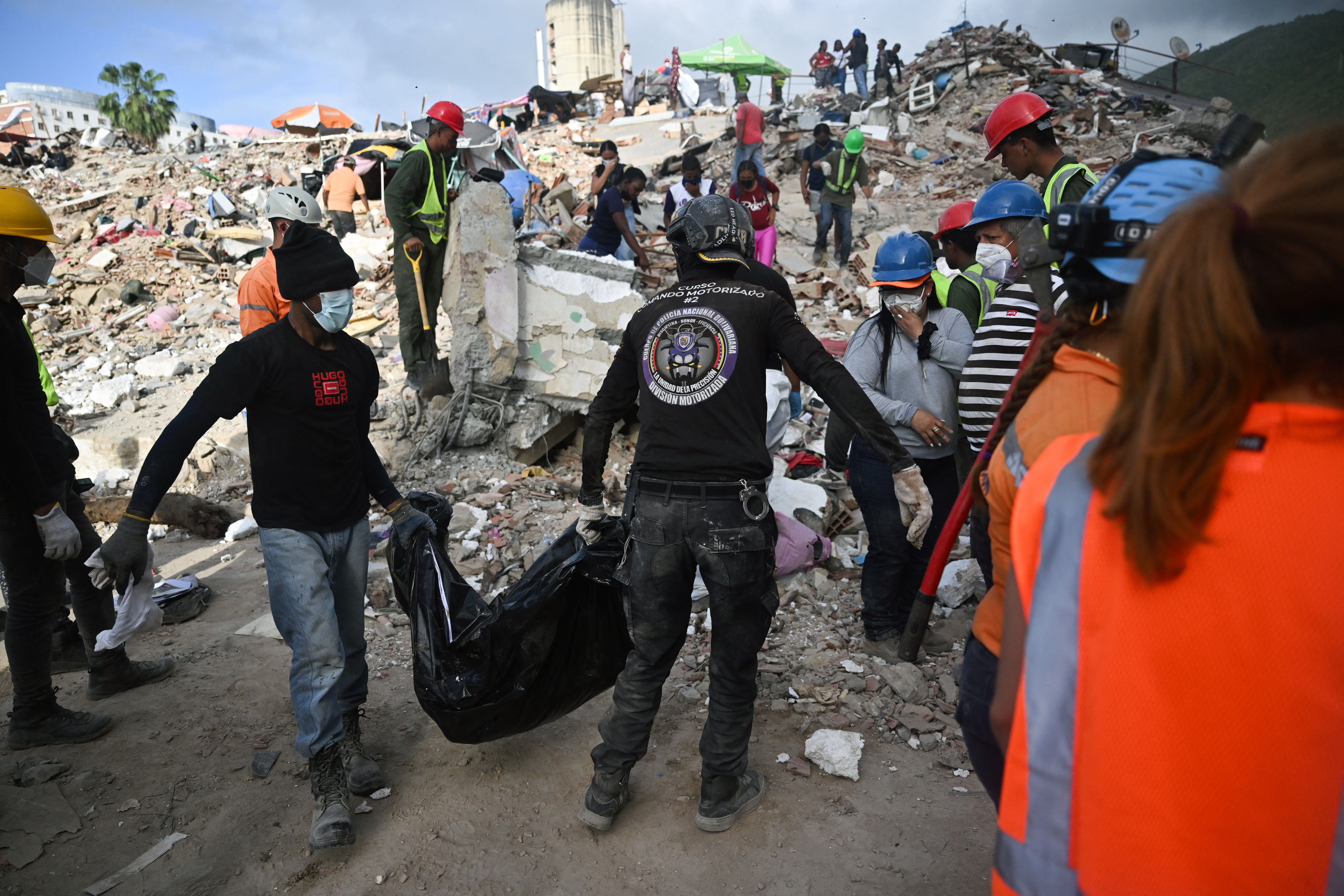 Volunteer rescue workers carry a body bag across the rubble of a collapsed building in Caraballeda, Venezuela, on July 17, 2026, following the June 24 earthquakes.