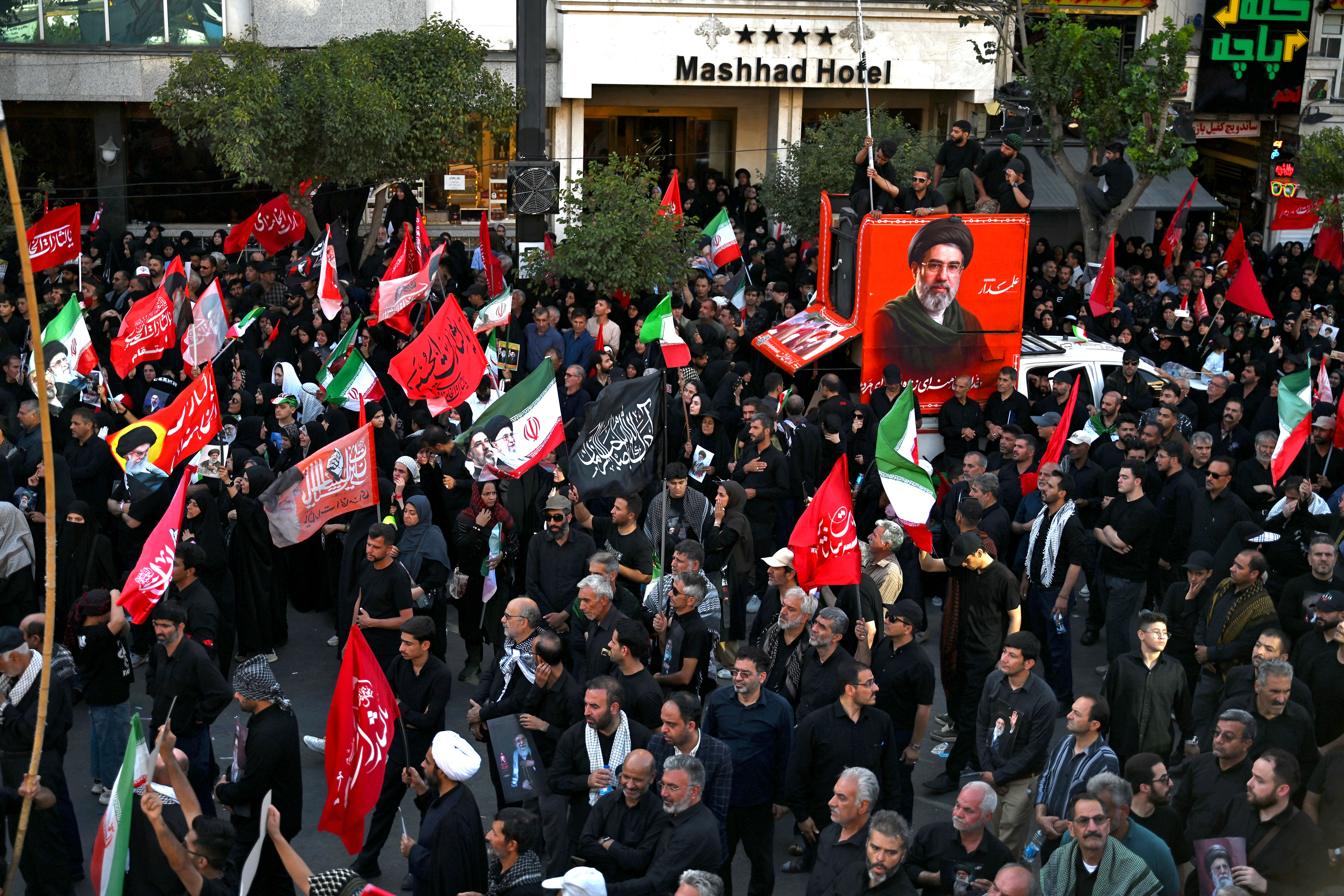 Crowds of mourners gather on a street around a portrait of Iran's supreme leader Mojtaba Khamenei ahead of the funeral procession of his father and predecessor, Ali Khamenei