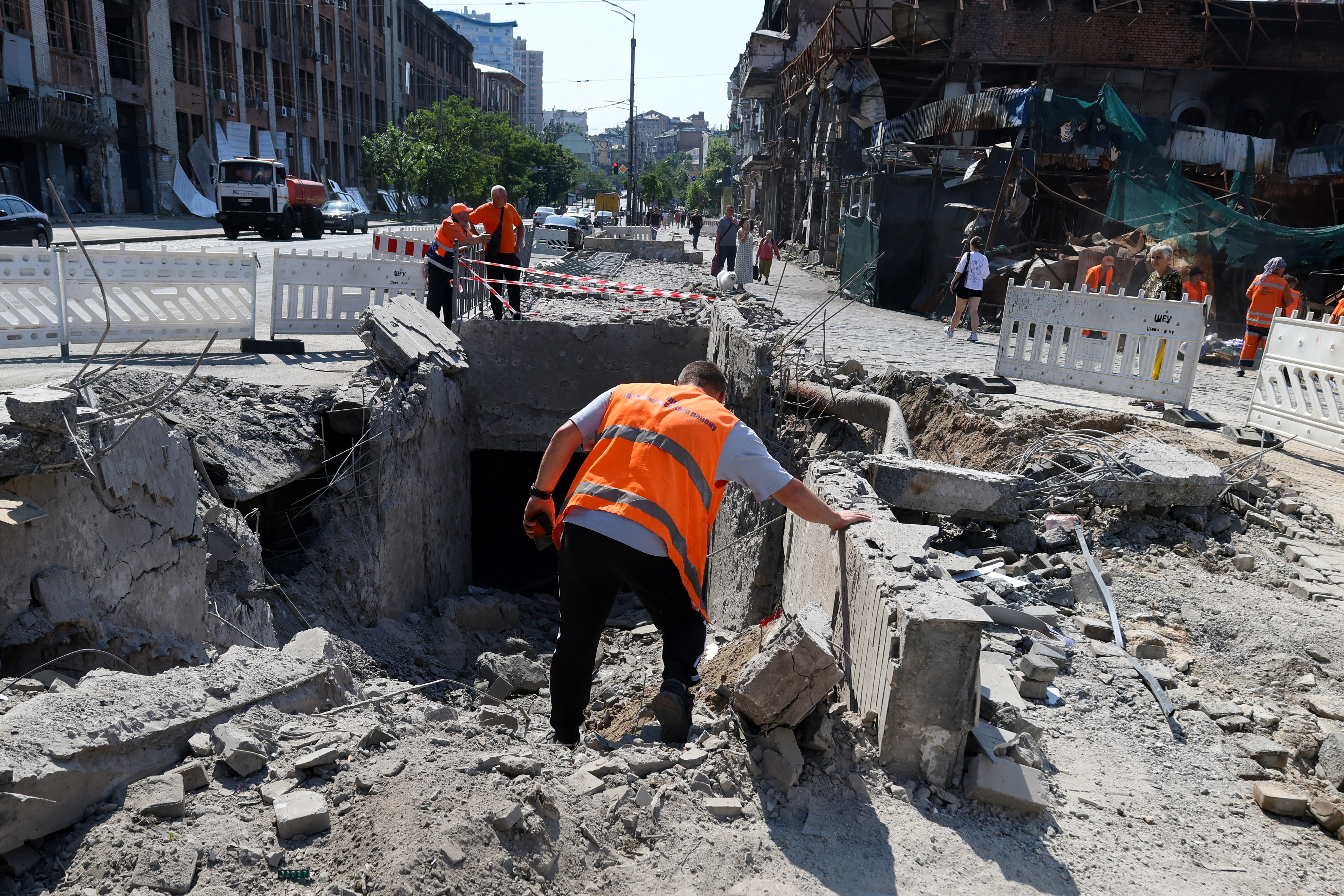 Communal workers clear debris from an underground pedestrian crossing damaged by missile strikes in Kyiv on July 19, 2026