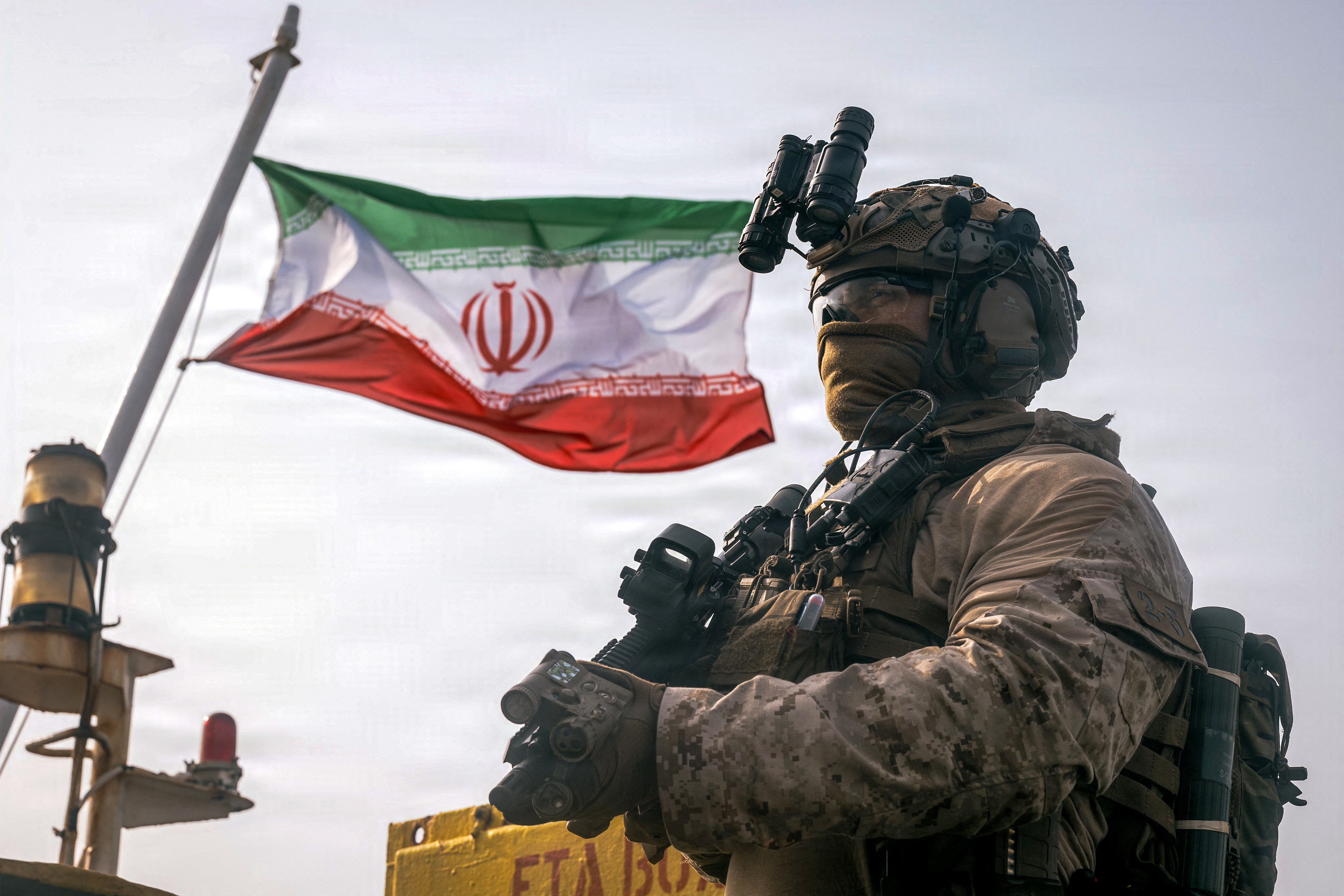 TOPSHOT - This US Marine Corps handout photograph taken on July 16, 2026, by US Central Command Public Affairs reportedly shows an Iranian flag flying behind a US Marine from the 11th Marine Expeditionary Unit during a verification boarding aboard M/T Wen Yao in the Gulf of Oman.