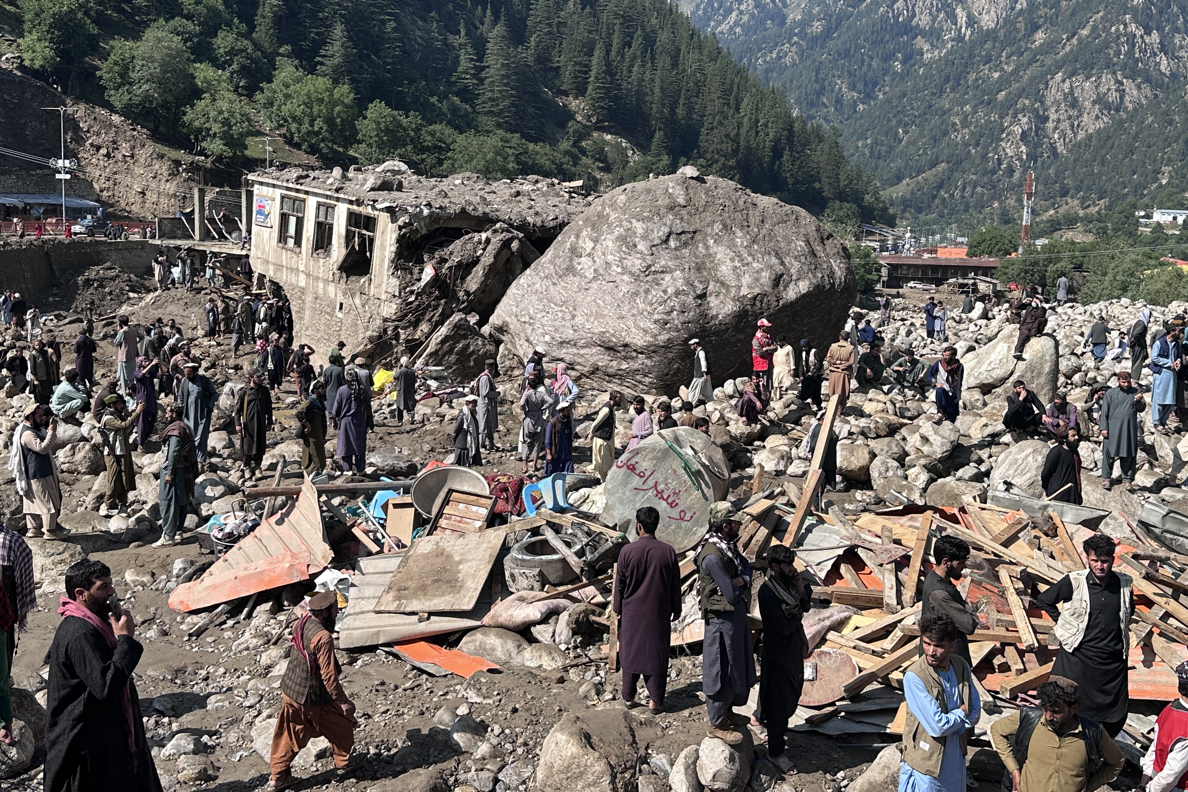 Afghan men stand amidst destroyed shops after flash floods hit Parun town in Afghanistan's Nuristan province on July 21, 2026.