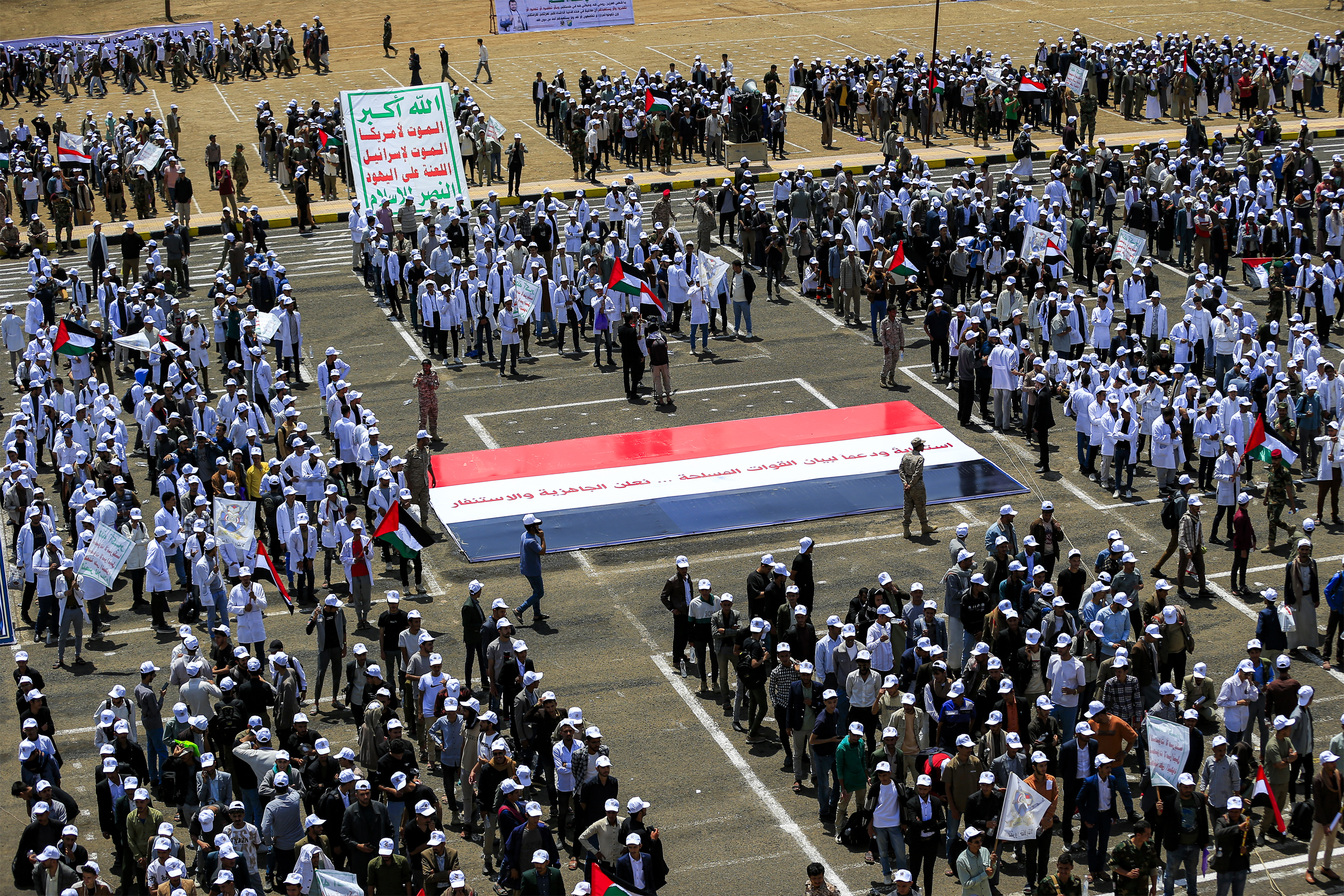 University students gather around a giant depiction of the Yemeni flag with a message of solidarity with the Houthi movement's forces during a demonstration to show their support for them amid escalating tensions with Saudi Arabia, at the Sanaa University campus in Yemen's Houthi-held capital Sanaa on July 22, 2026.