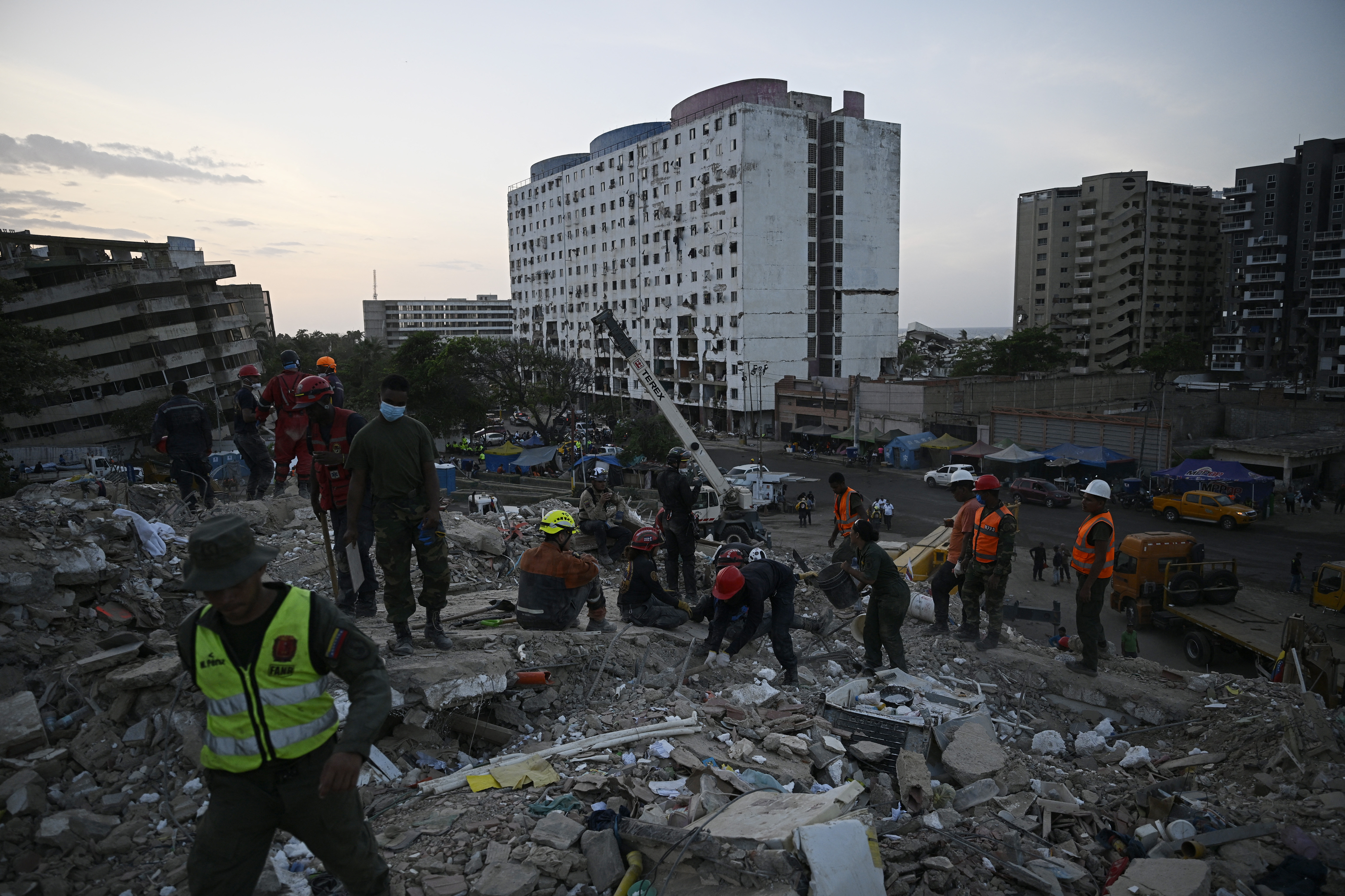 Rescue teams and volunteers search for bodies amid the rubble of a collapsed building in Caraballeda, Venezuela, on July 24, 2026, one month after an earthquake struck the area.
