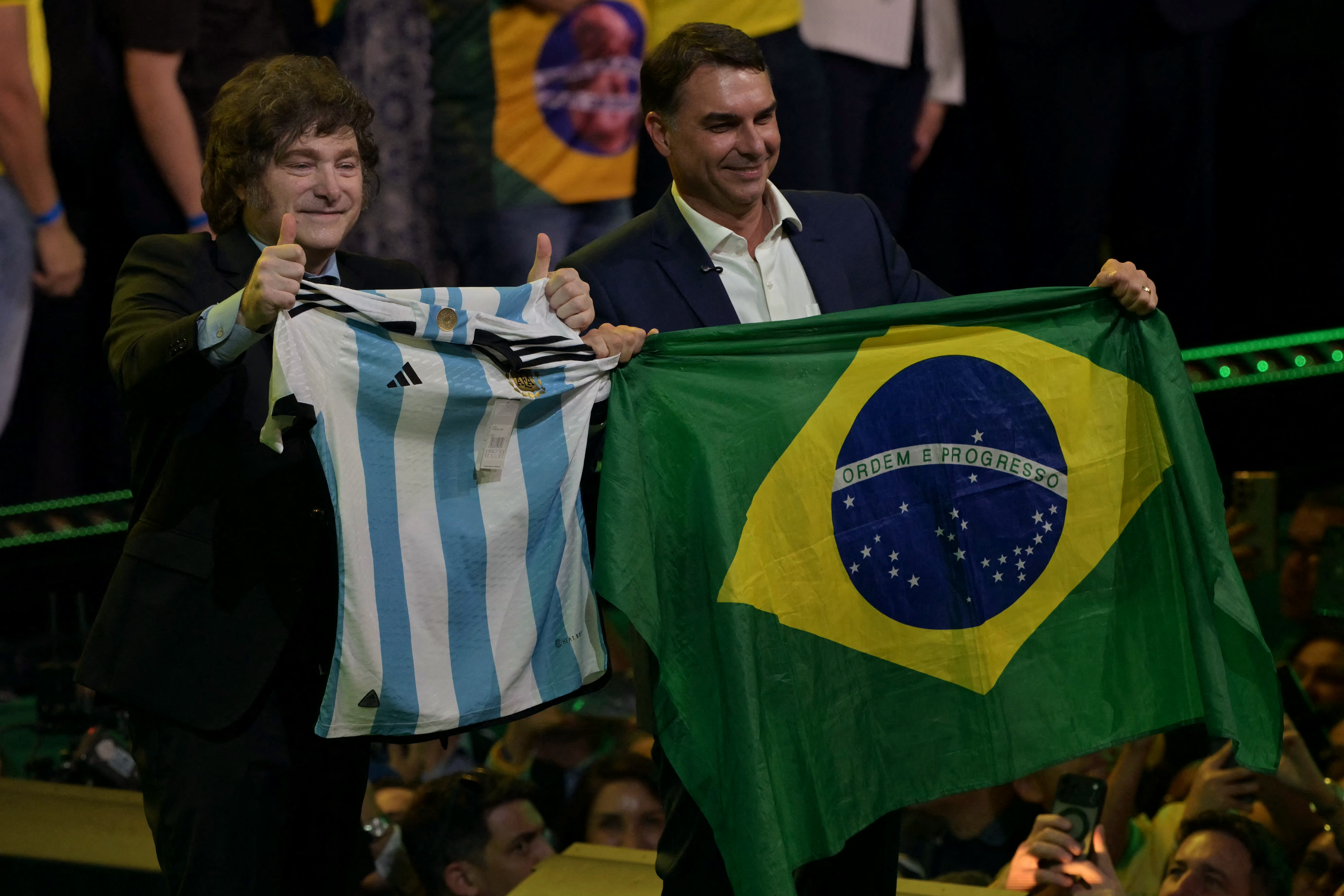 Argentina's President Javier Milei holds a national football jersey next to Brazil's right-wing presidential hopeful Flavio Bolsonaro holding a national flag during the launching of the latter's candidacy within the Liberal Party convention, in Sao Paulo, Brazil on July 25, 2026.