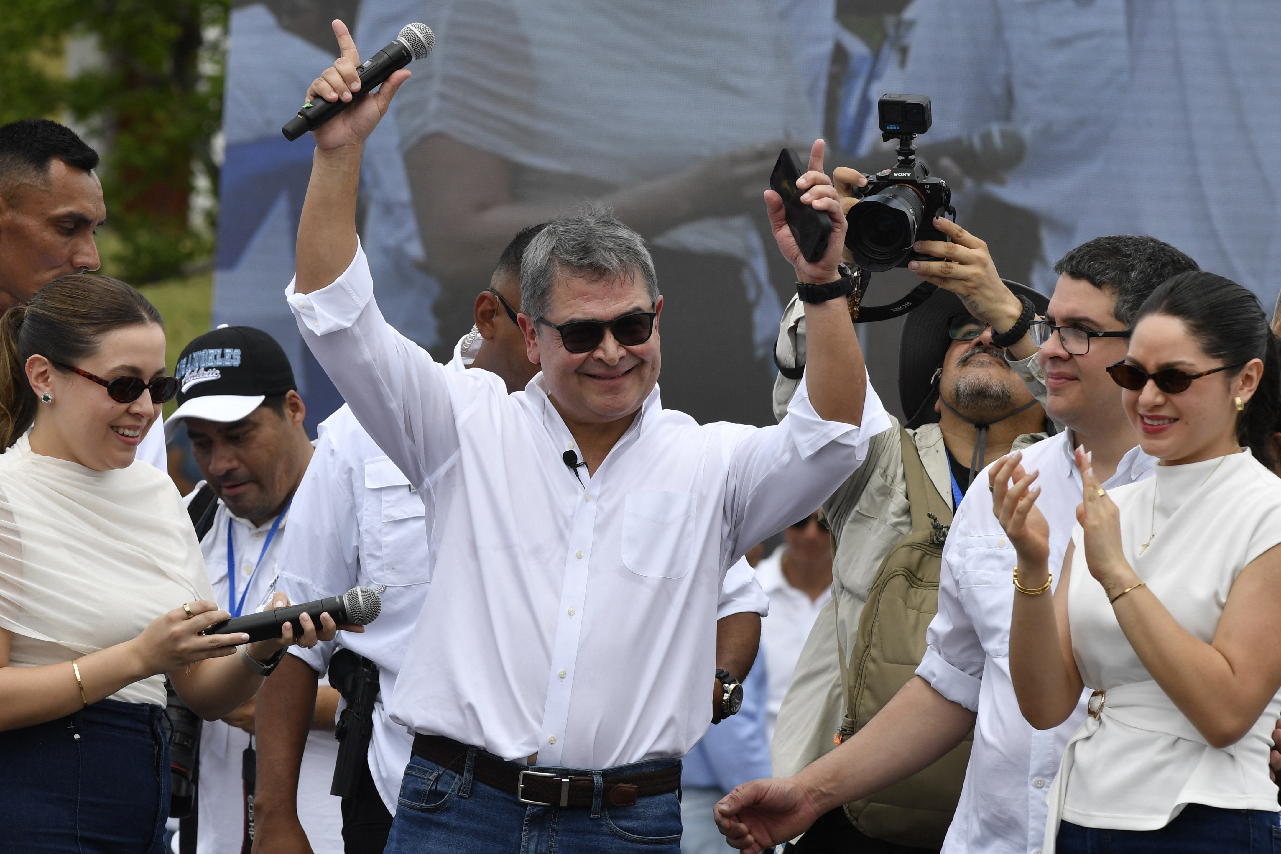 Former Honduras' President (2014-2022) Juan Orlando Hernandez waves flanked by his daughters Daniela (L) and Isabela (R) during a welcome event at an estate, in Comayagua, 80 km north of Tegucigalpa, on July 26, 2026.
