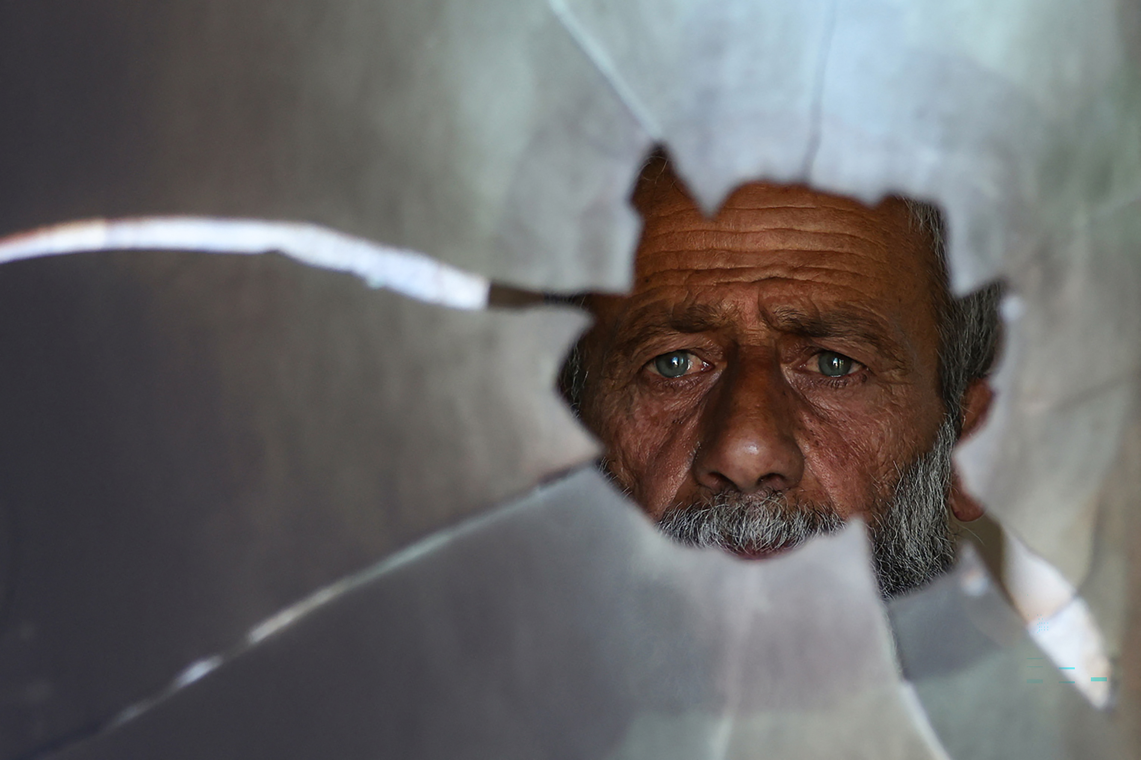 A Palestinian man checks a broken window at the damaged Al-Taqwa mosque, whose entrance was torched and walls were daubed with Hebrew graffiti in an attack allegedly carried out by Israeli settlers in the Palestinian village of Al-Tuwani, south of Yatta, near Hebron in the occupied West Bank on July 19, 2026. (Photo by HAZEM BADER / AFP)