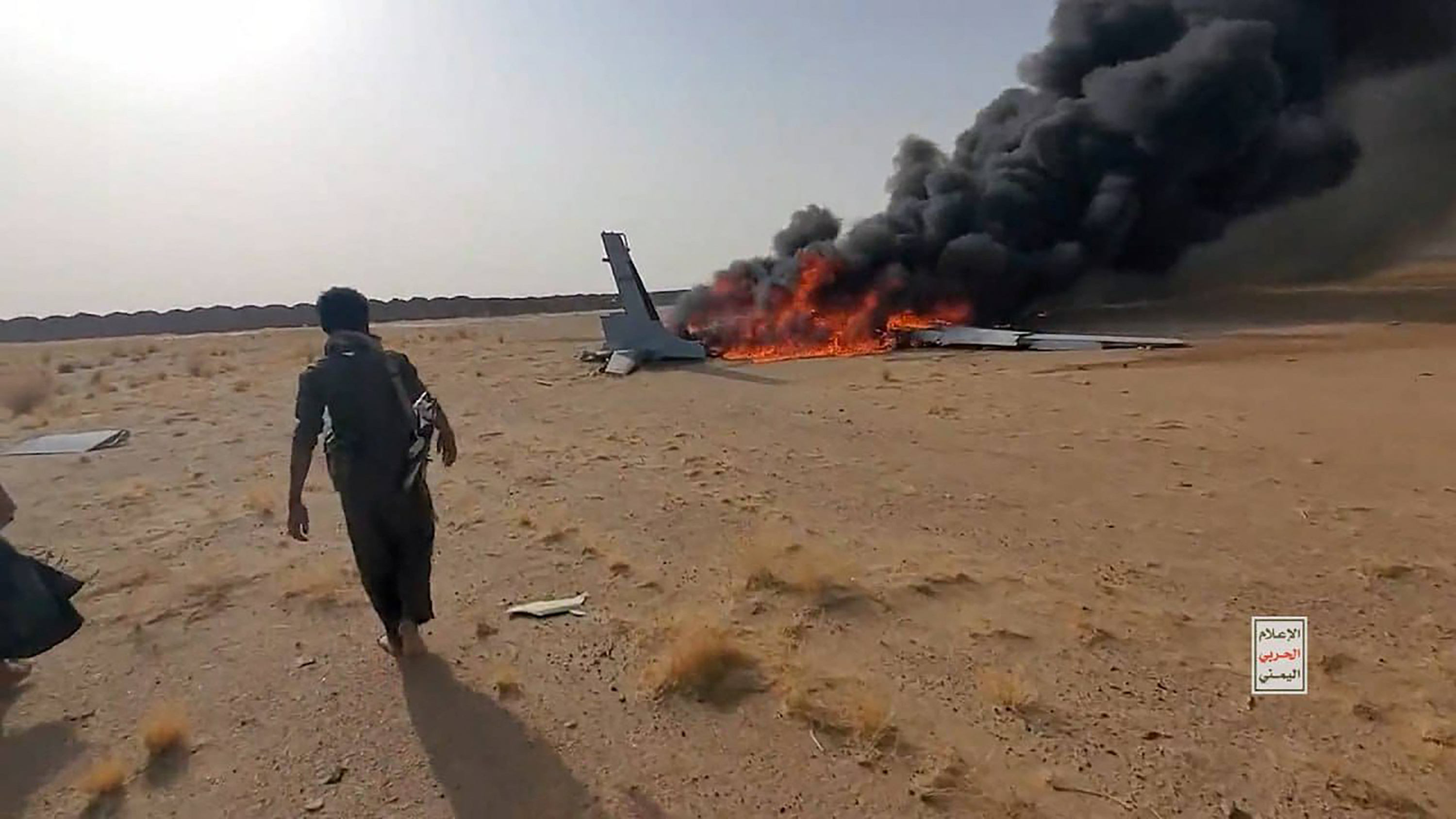 A handout image made available by the Ansarullah Media Center on July 26, 2026, shows an Iran-backed Houthi rebel walking towards the burning wreckage of what the group says is of a downed Saudi drone, in the northwest of Yemen's al-Jawf governorate.