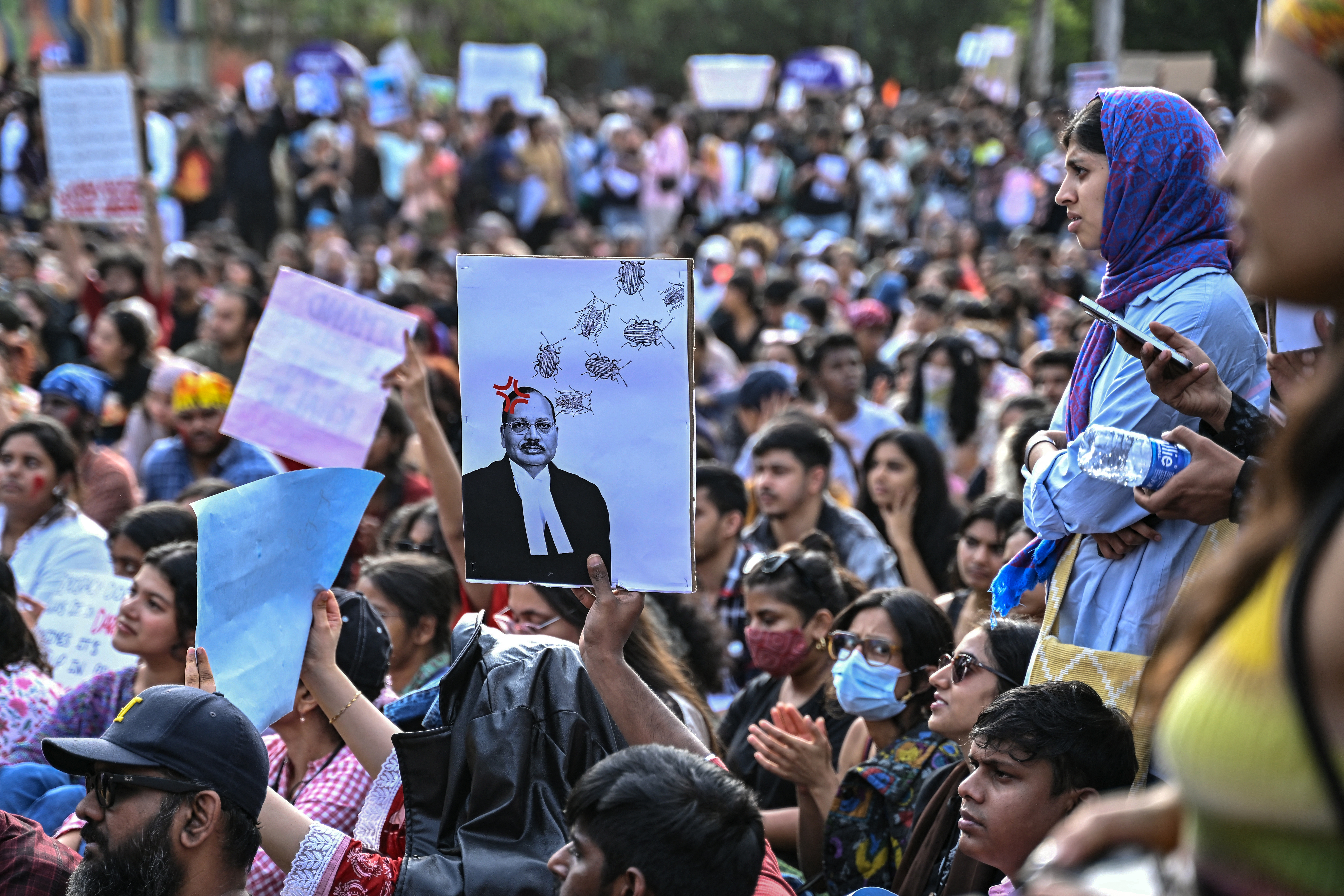 People hold placards during a victory gathering organised by the All India Students' Association (AISA) in Bengaluru on July 26, 2026 a day after the Cockroach Janta Party (CJP) ended their protest in New Delhi's Jantar Mantar following the resignation of India's Education Minister Dharmendra Pradhan over alleged NEET examination irregularities.