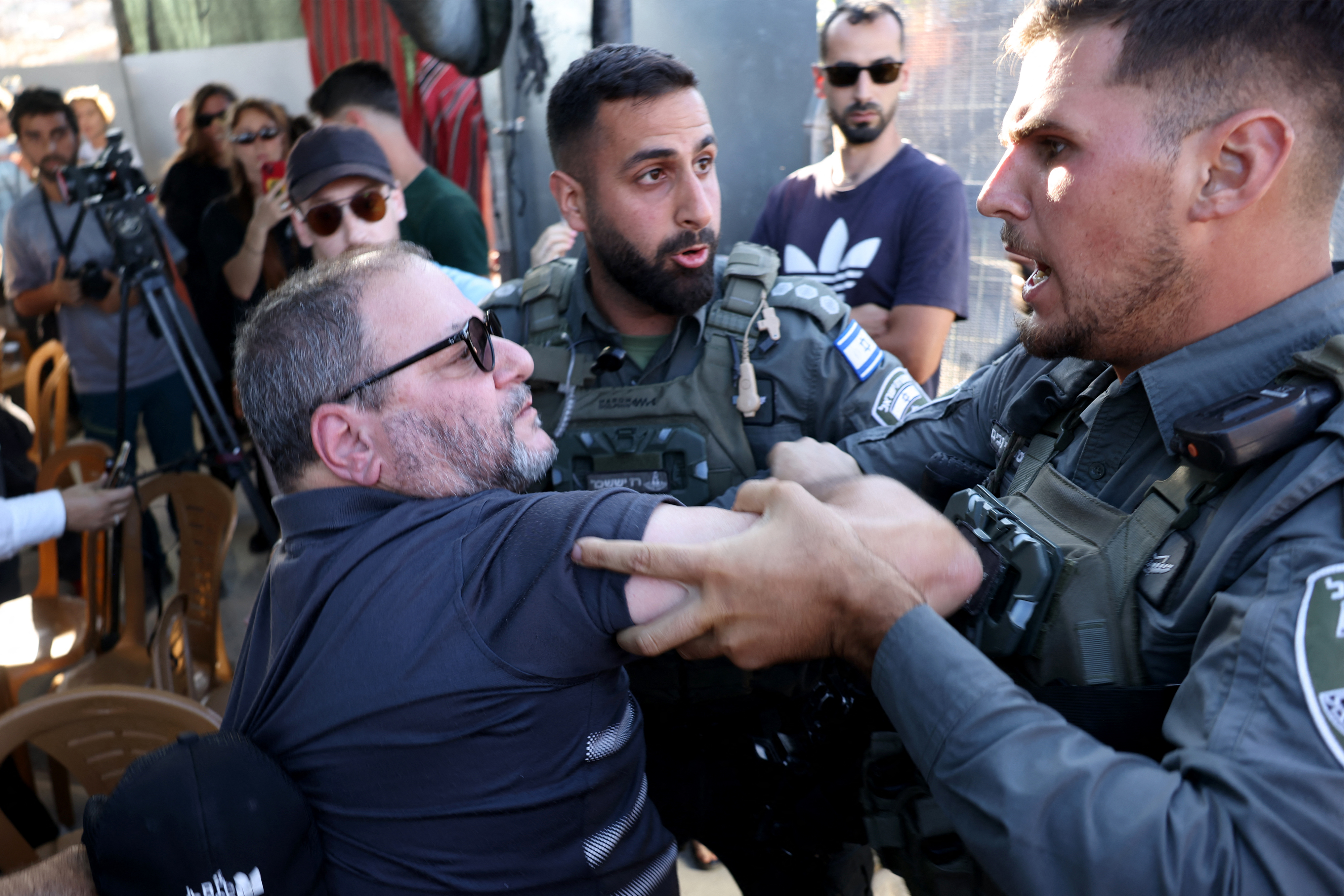 Israeli Knesset member Ofer Cassif (L) confronts members of Israel's security forces as Palestinians, foreigners and israeli activists attend a memorial ceremony for slain Palestinian activist Awdah Hathaleen on the anniversary of his death Umm al-Khair village in the occupied West Bank city of Hebron on July 28, 2026.