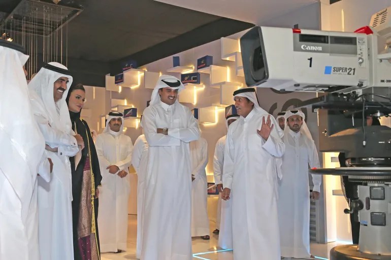 Sheikh Hamad bin Khalifa along with his wife Sheikha Moza and his son Sheikh Tamim are being shown an Al Jazeera studio by the author. [Al Jazeera]