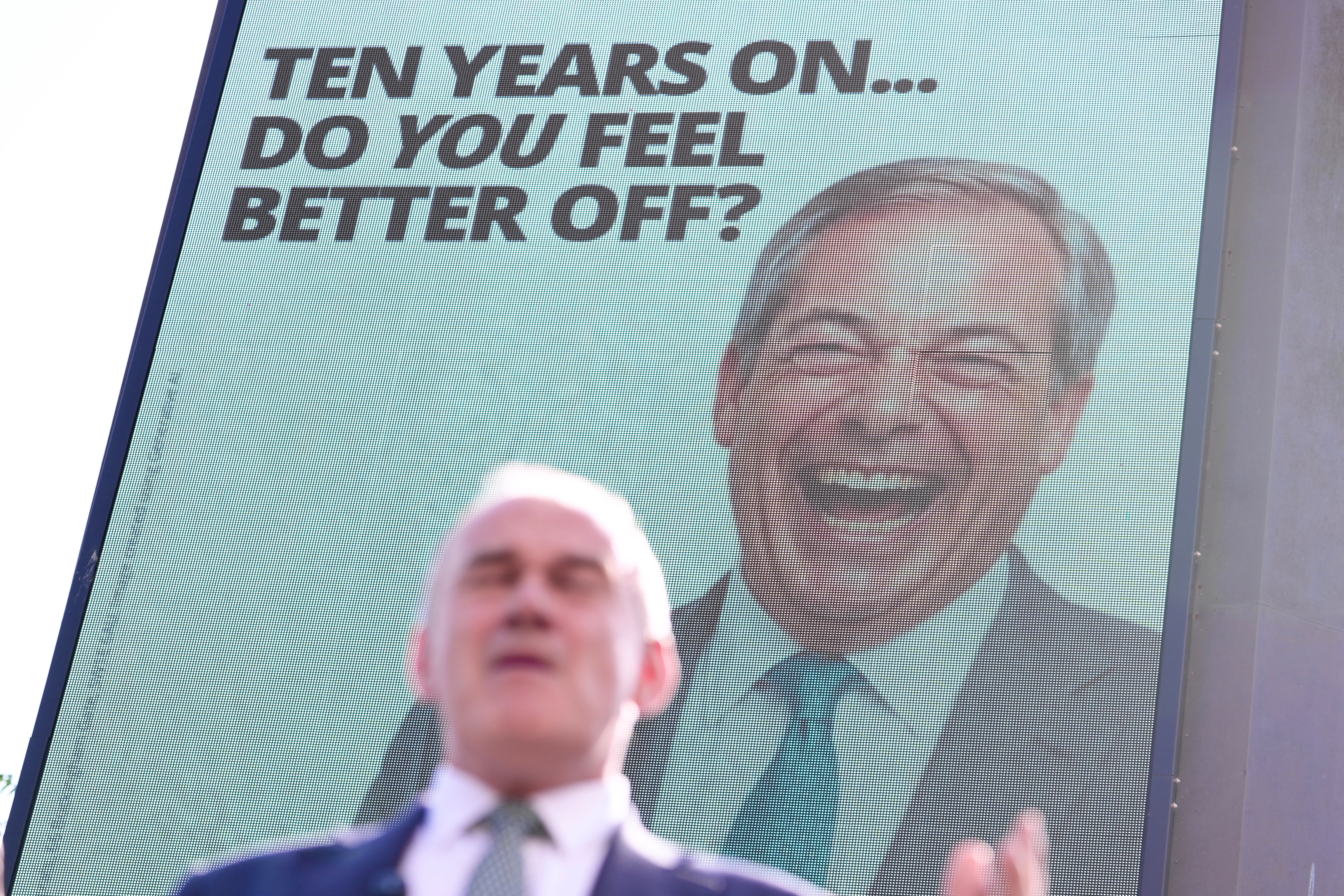 Liberal Democrat Leader Ed Davey stands in front of a billboard showing Reform UK leader Nigel Farage as he unveils a new national billboard campaign to mark the 10th anniversary of the Brexit referendum in London, Tuesday, June 23, 2026. (AP Photo/Kin Cheung)