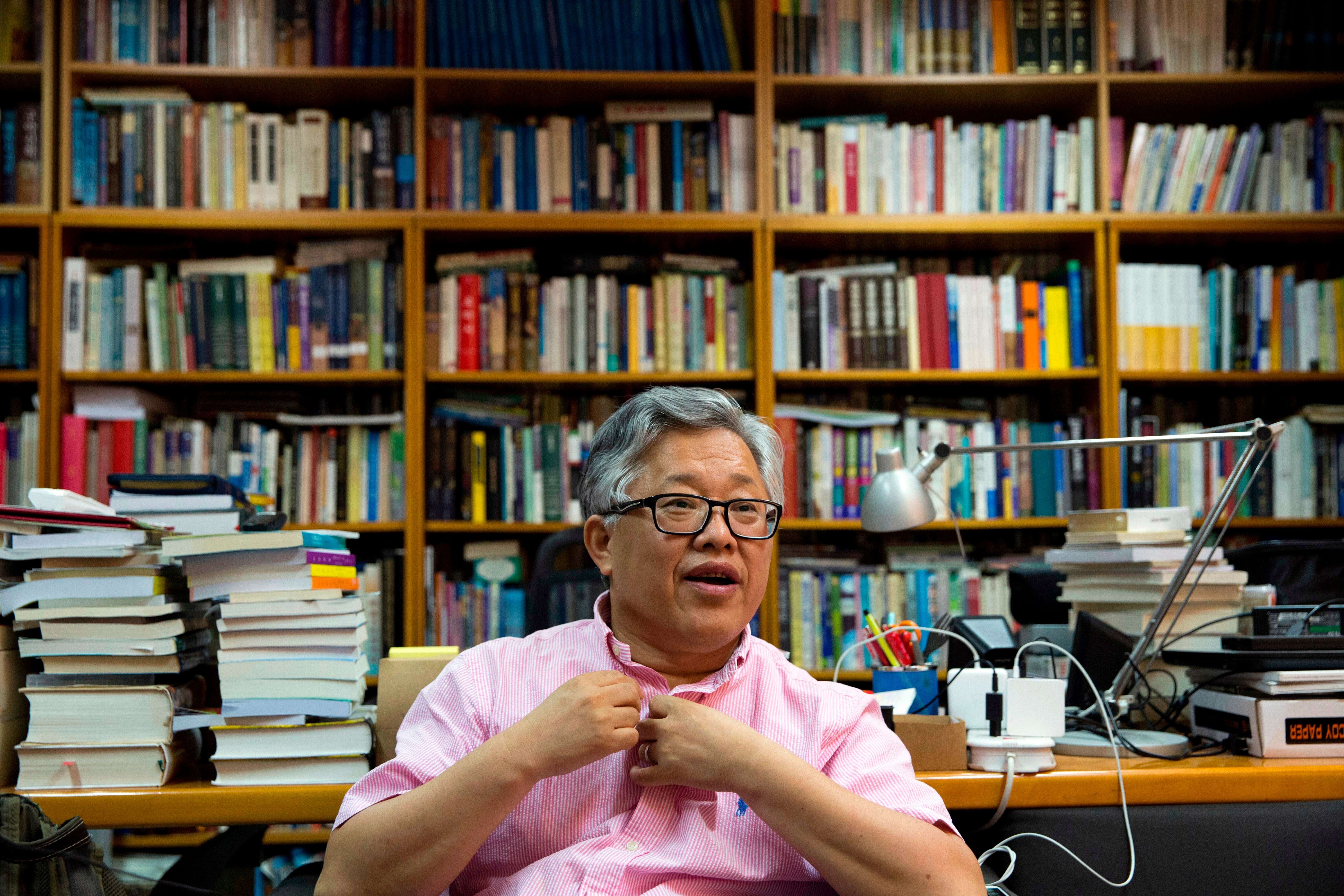 A man sits in a room with lots of books around him
