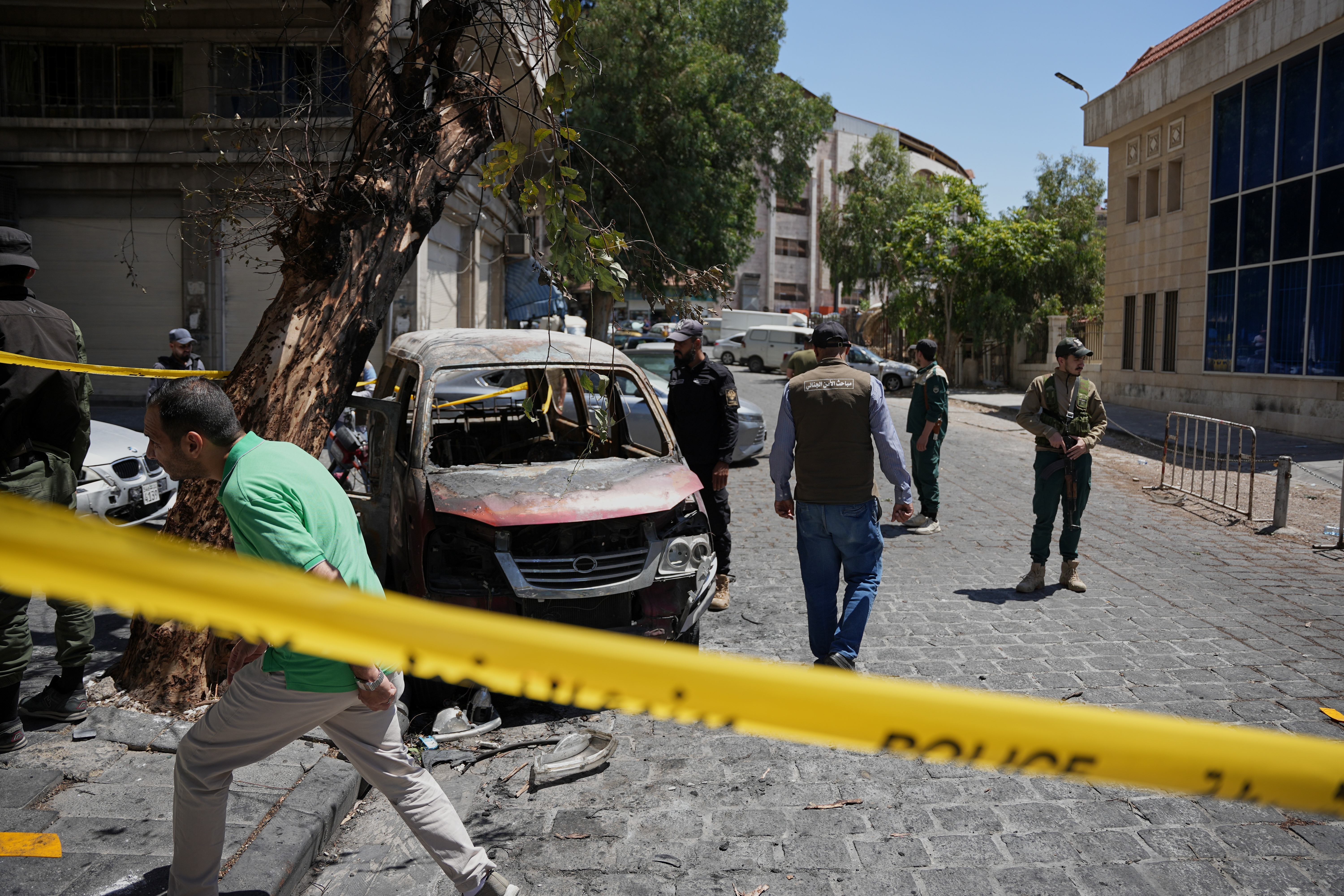 Security personnel inspect a burned vehicle.