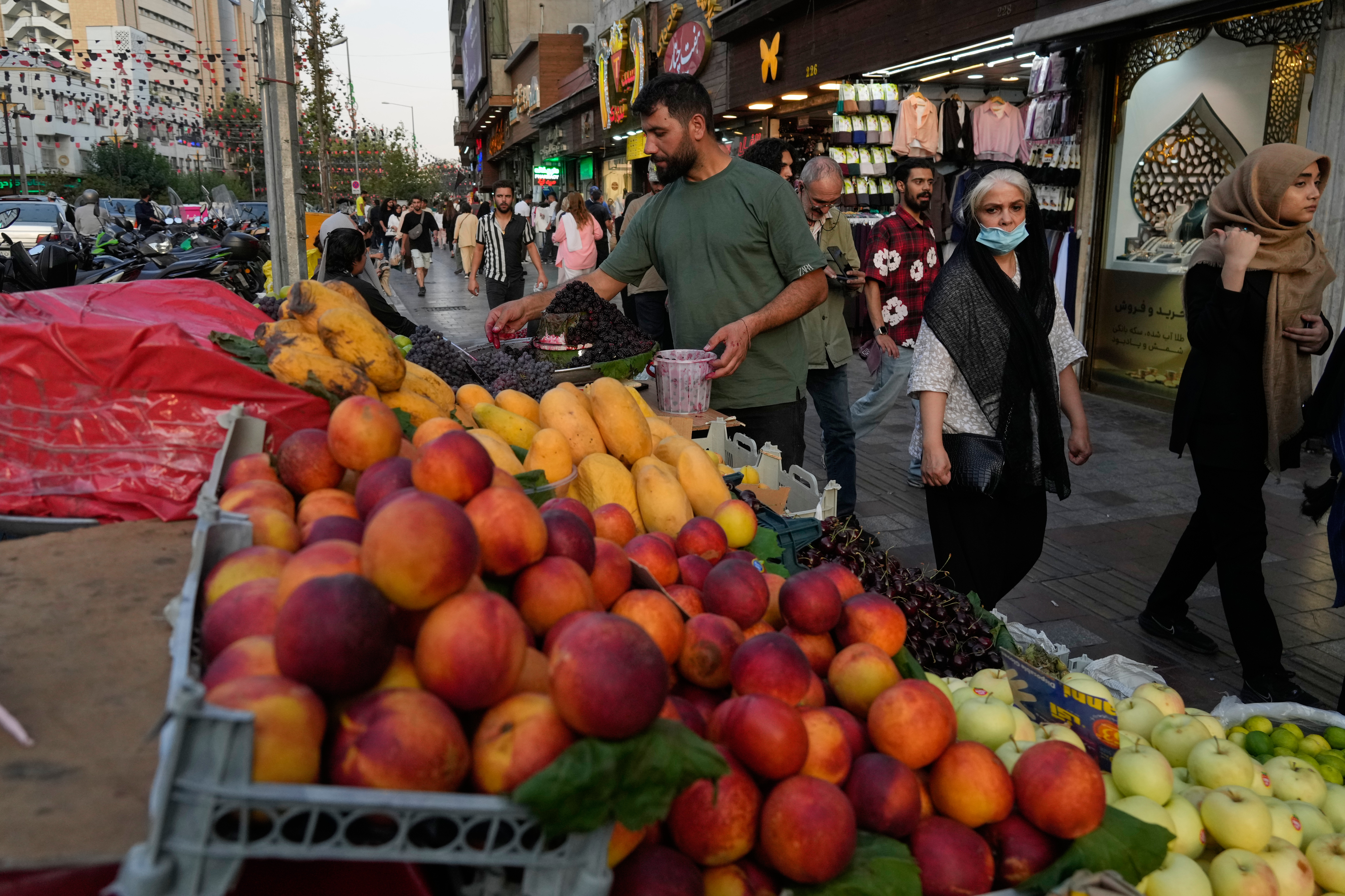 A fruit seller arranges fruits at his stall at Tajrish Square in northern Tehran, Iran, Monday, July 13, 2026