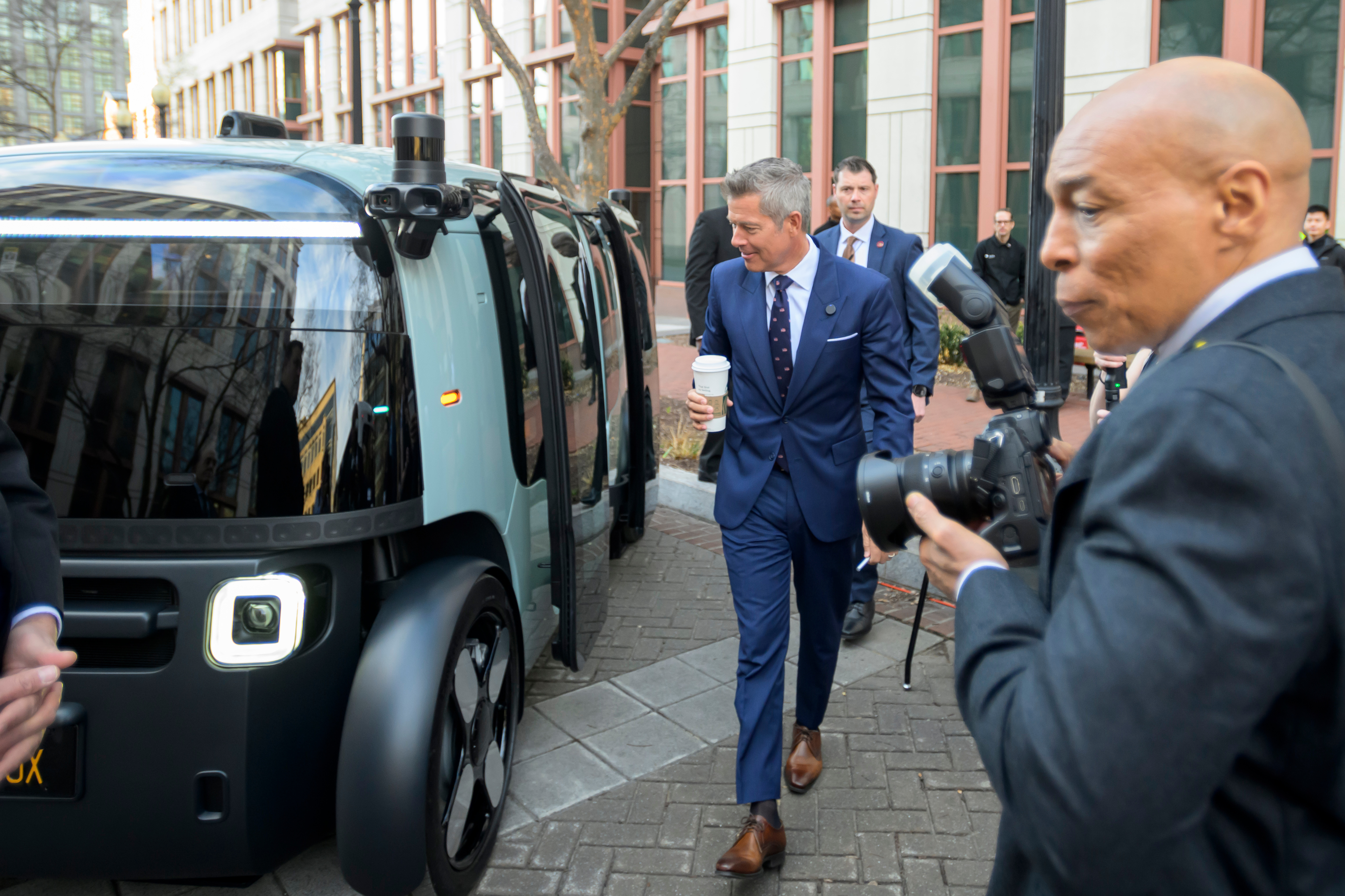 Transportation Secretary Sean Duffy, center, takes a look at the exterior of a Zoox autonomous vehicle during the National AV Safety Forum at the U.S. Department of Transportation, Tuesday, March 10, 2026, in Washington. (AP Photo/Rod Lamkey, Jr.)