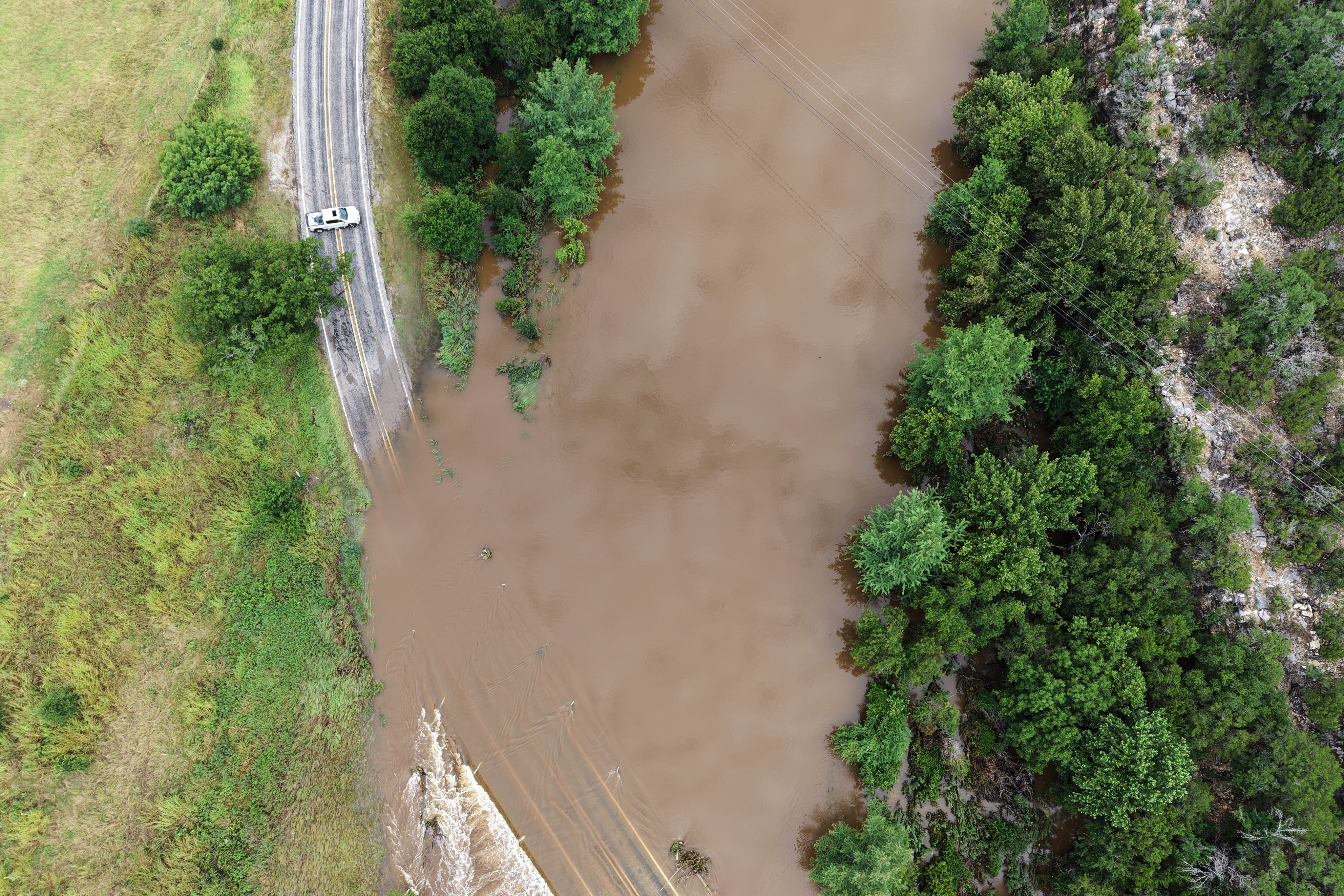 The Guadalupe River floods a crossing after a series of storms on Friday, July 17, 2026, in Hunt, Texas. (AP Photo/Gerald Herbert)
