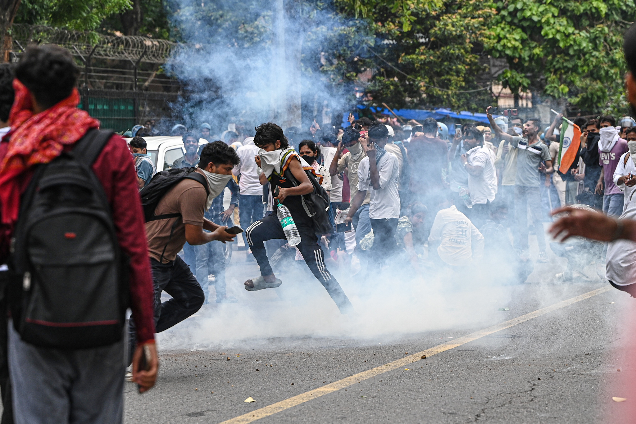 Supporters of the Cockroach Janta Party try to neutralize a tear gas shell fired by police as they attempt to march toward India's Parliament, demanding the resignation of the education minister, in New Delhi, India, Monday, July 20, 2026. (AP Photo/Prakash Singh)