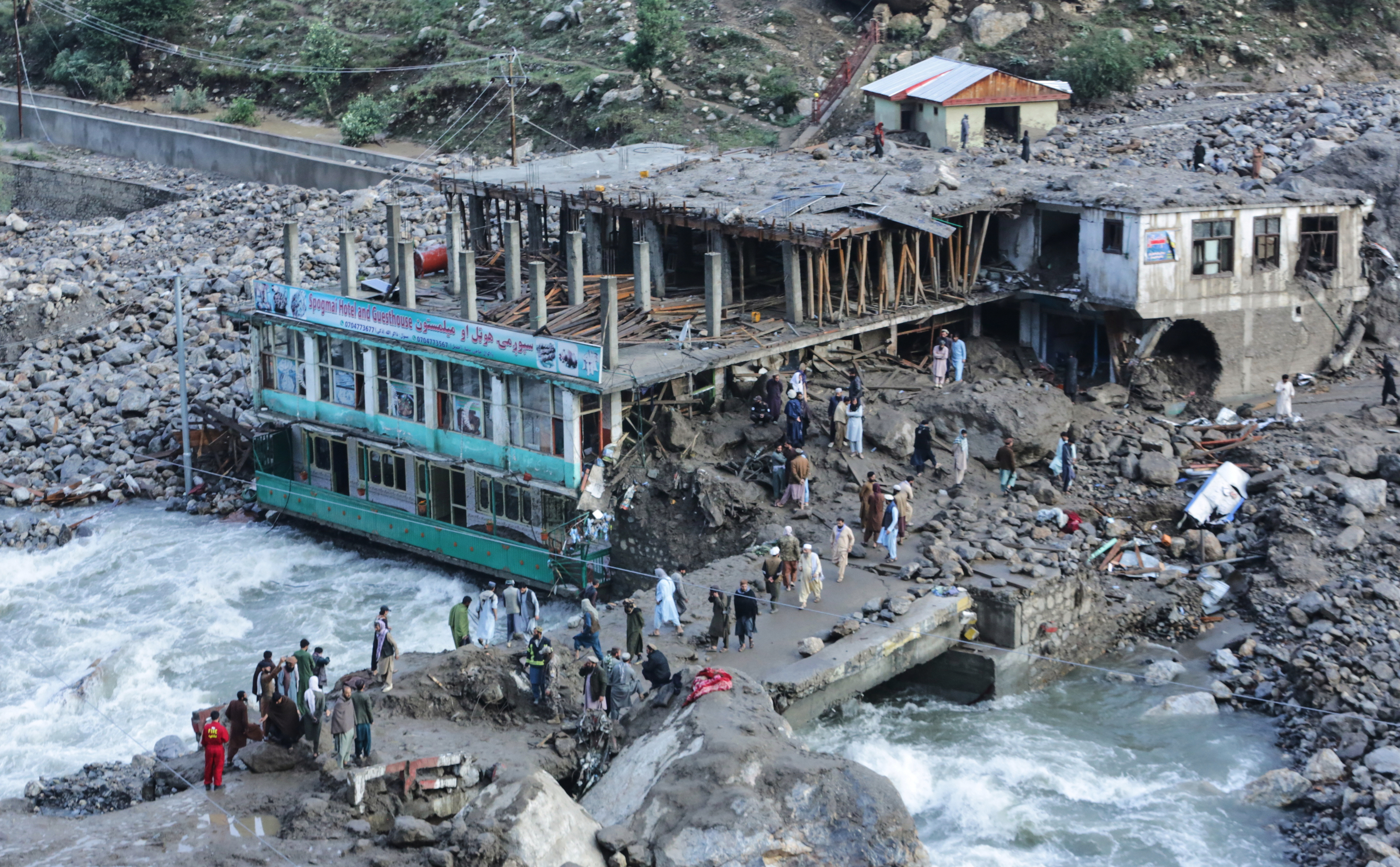 Residents and rescue workers inspect buildings damaged by heavy flooding in the eastern province of Nuristan, Afghanistan, Tuesday, July 21, 2026. (AP Photo/Wahidullah Kakar)