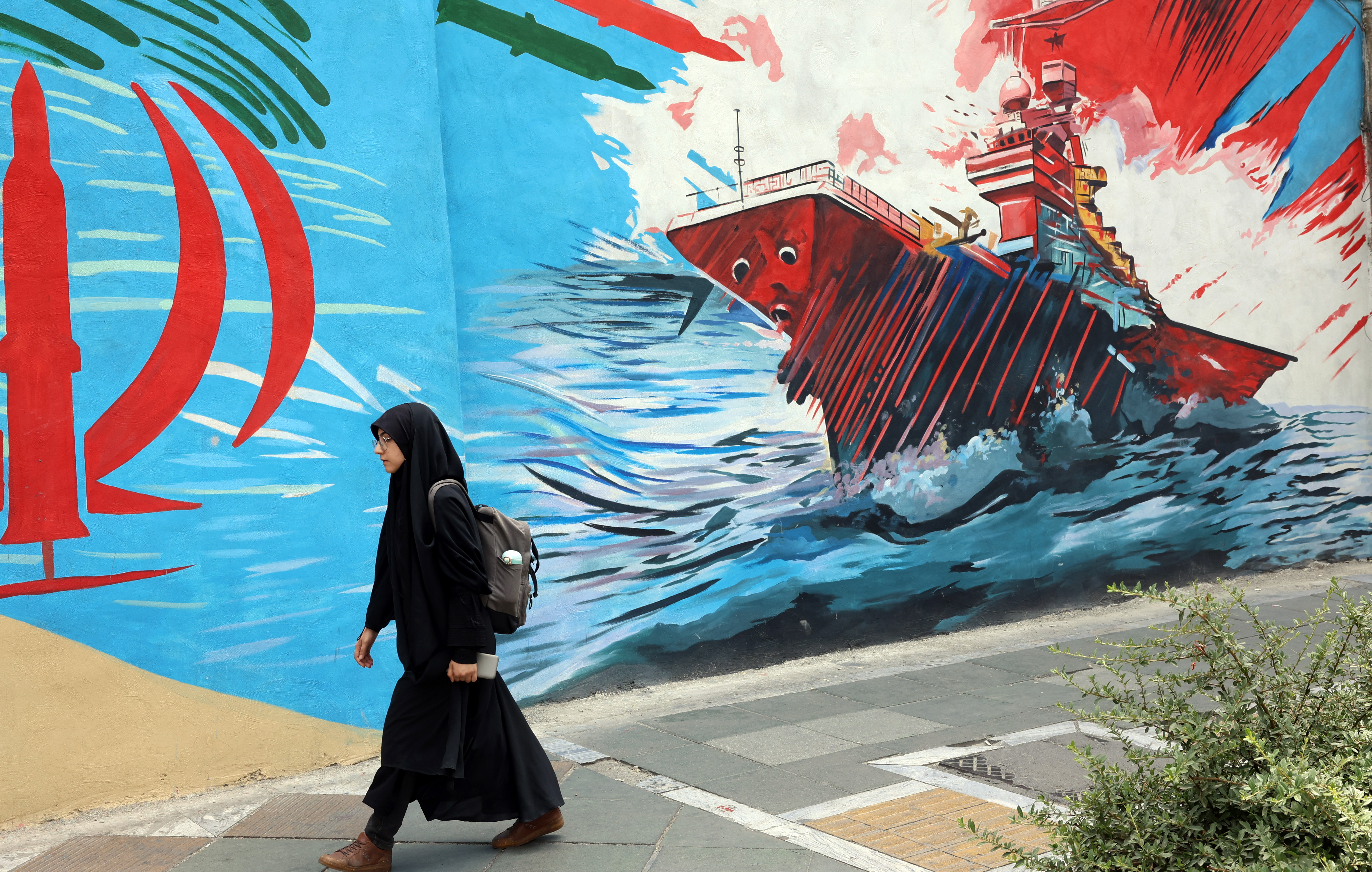 epa13122572 A woman walks next to anti-US graffiti on a street in Tehran, Iran, 20 July 2026. The US continued strikes against Iran for the ninth consecutive night on 19 July targeting 'military command centers, air defense and coastal surveillance sites, maritime capabilities, missile and drone launch sites', the US Central Command (CENTCOM) announced, amid the continuing conflict between Iran and US over the Strait of Hormuz. EPA/ABEDIN TAHERKENAREH RESTRICTIONS: NO Access Israel Media/Persian Language TV Stations Outside Iran/Strictly No Access BBC Persian/VOA Persian/Manoto TV/Iran International TV. (As mandated by Iran's Directorate General for Foreign Media) --
