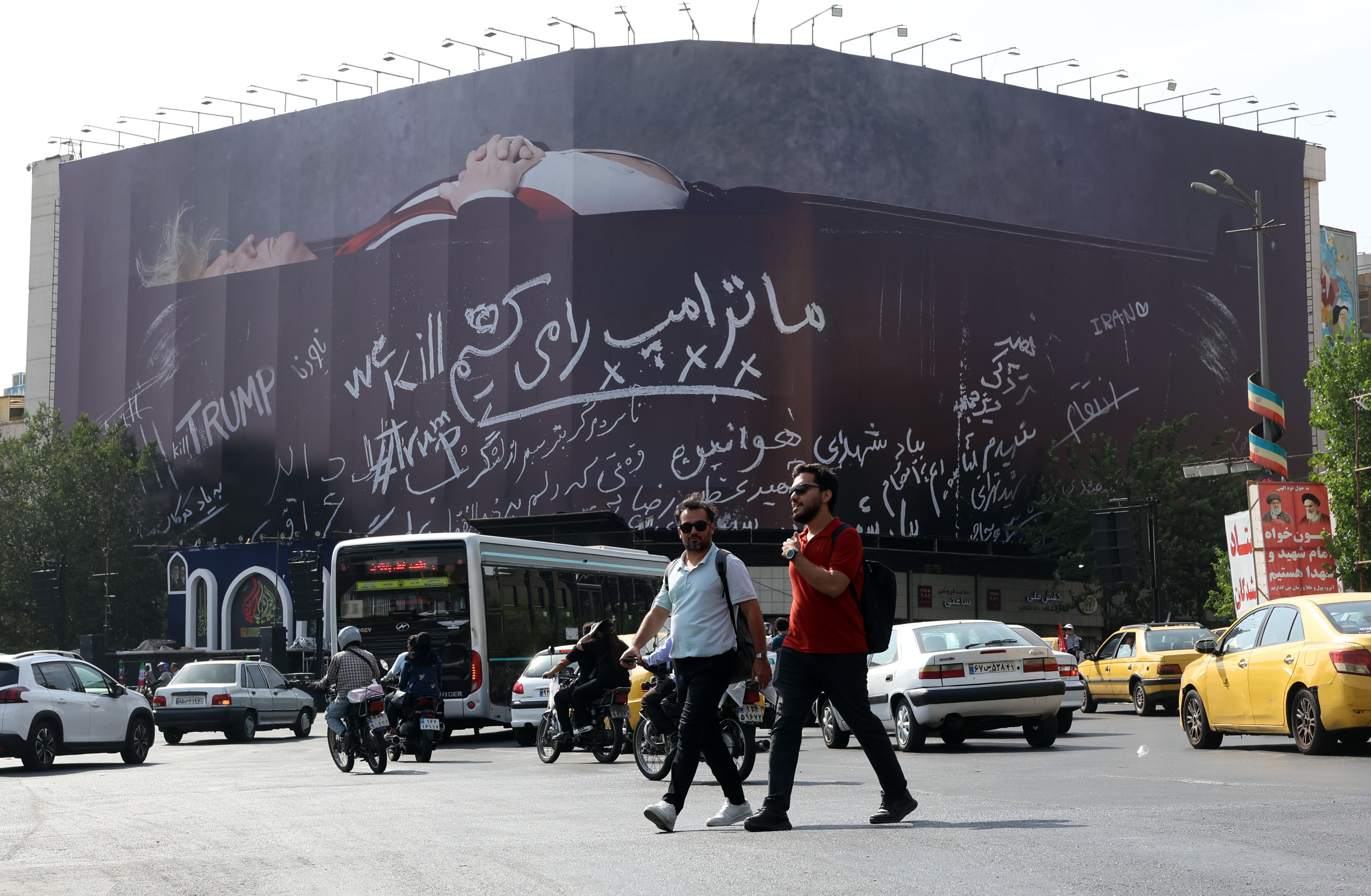epa13126439 Iranians walk past an anti-US billboard depicting US President Donald Trump in a coffin alongside the slogan 'We Kill Trump' at Enghelab Square in Tehran, Iran, 22 July 2026. Tensions between Iran and the US continue over the Strait of Hormuz following US strikes on several locations across Iran. EPA/ABEDIN TAHERKENAREH RESTRICTIONS: NO Access Israel Media/Persian Language TV Stations Outside Iran/Strictly No Access BBC Persian/VOA Persian/Manoto TV/Iran International TV. (As mandated by Iran's Directorate General for Foreign Media) --