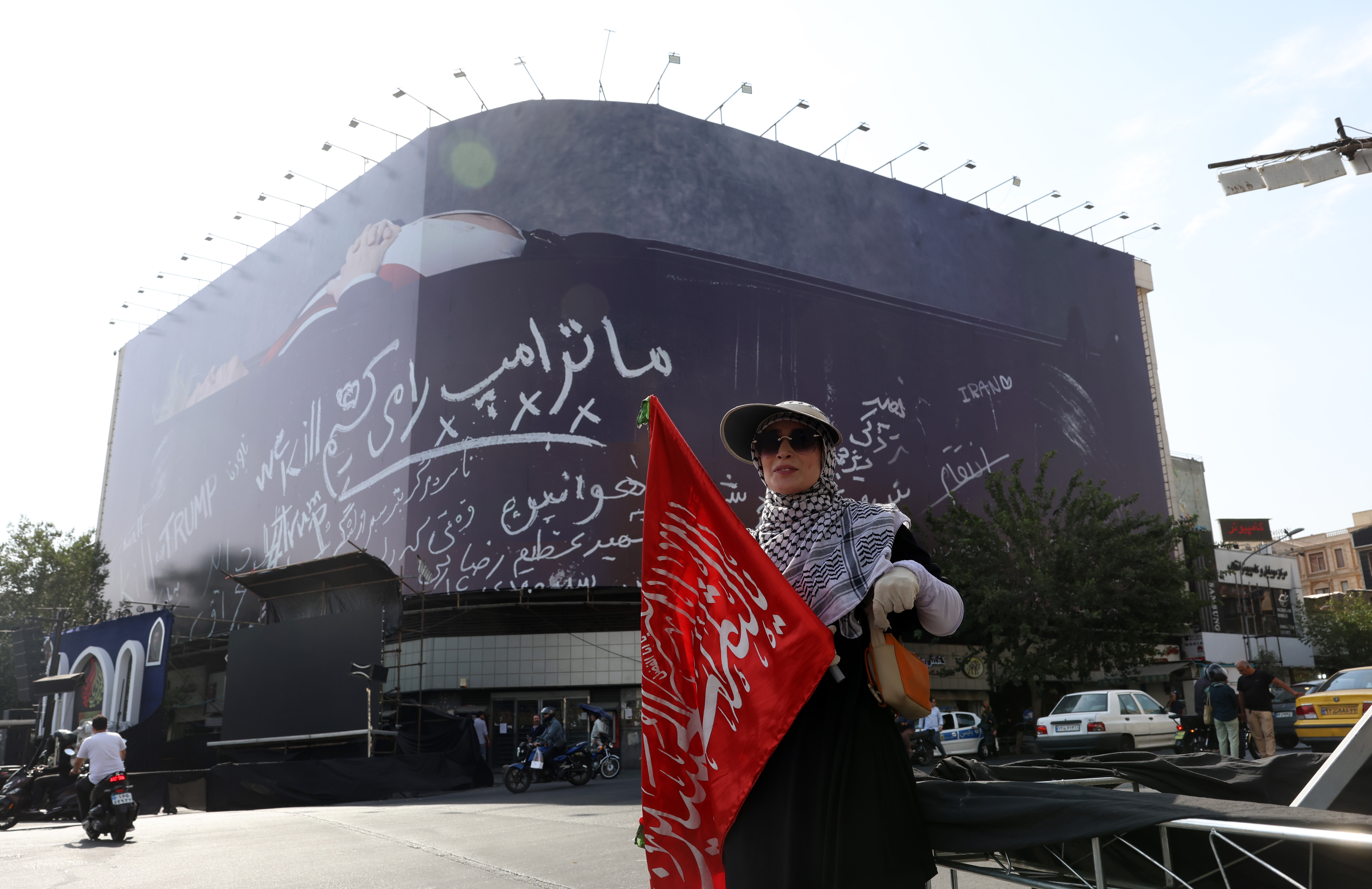 epa13126441 An Iranian woman stands next to an anti-US billboard depicting US President Donald Trump in a coffin alongside the slogan 'We Kill Trump' at Enghelab Square in Tehran, Iran, 22 July 2026. Tensions between Iran and the US continue over the Strait of Hormuz following US strikes on several locations across Iran. EPA/ABEDIN TAHERKENAREH RESTRICTIONS: NO Access Israel Media/Persian Language TV Stations Outside Iran/Strictly No Access BBC Persian/VOA Persian/Manoto TV/Iran International TV. (As mandated by Iran's Directorate General for Foreign Media) --