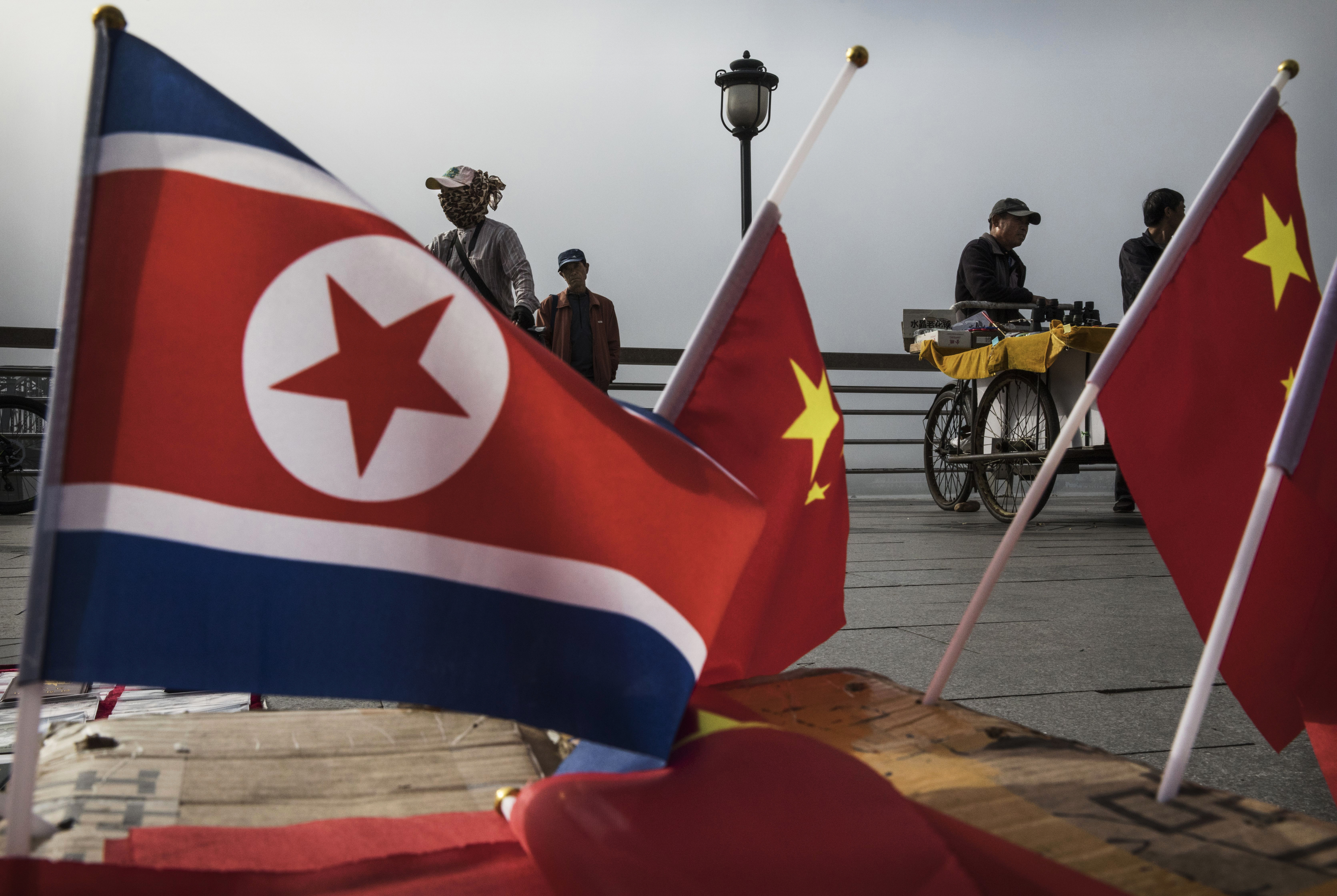 DANDONG, CHINA - MAY 24: (CHINA OUT) Chinese vendors sell North Korea and China flags on the boardwalk next to the Yalu river in the border city of Dandong, Liaoning province, northern China across from the city of Sinuiju, North Korea on May 24, 2017 in Dandong, China. China has long been North Korea's main ally and trading partner, but relations are increasingly strained by continued missile testing and provocations by the regime of Kim Jong Un. The North is almost entirely dependent on trade with China to feeds its impoverished economy, yet it has ignored calls by the international community to halt its nuclear and ballistic missile weapons programs. At least three-quarters of trade between the two nations flows through points along its 880-mile long shared border, a divide that reveals stark contrasts in development. Cities such as Dandong boast high-rise buildings and advanced infrastructure, and the Friendship Bridge serves as the conduit for the bulk of trade. From hired boats along the Yalu river, Chinese tourists peer into the reclusive North, marked by soldiers, meagre villages, and depleted farmland. The United States has pressured China to do more to leverage its clout with North Korea, though Beijing remains concerned that outright regime collapse in Pyongyang could trigger a rush of refugees across the border. (Photo by Kevin Frayer/Getty Images)