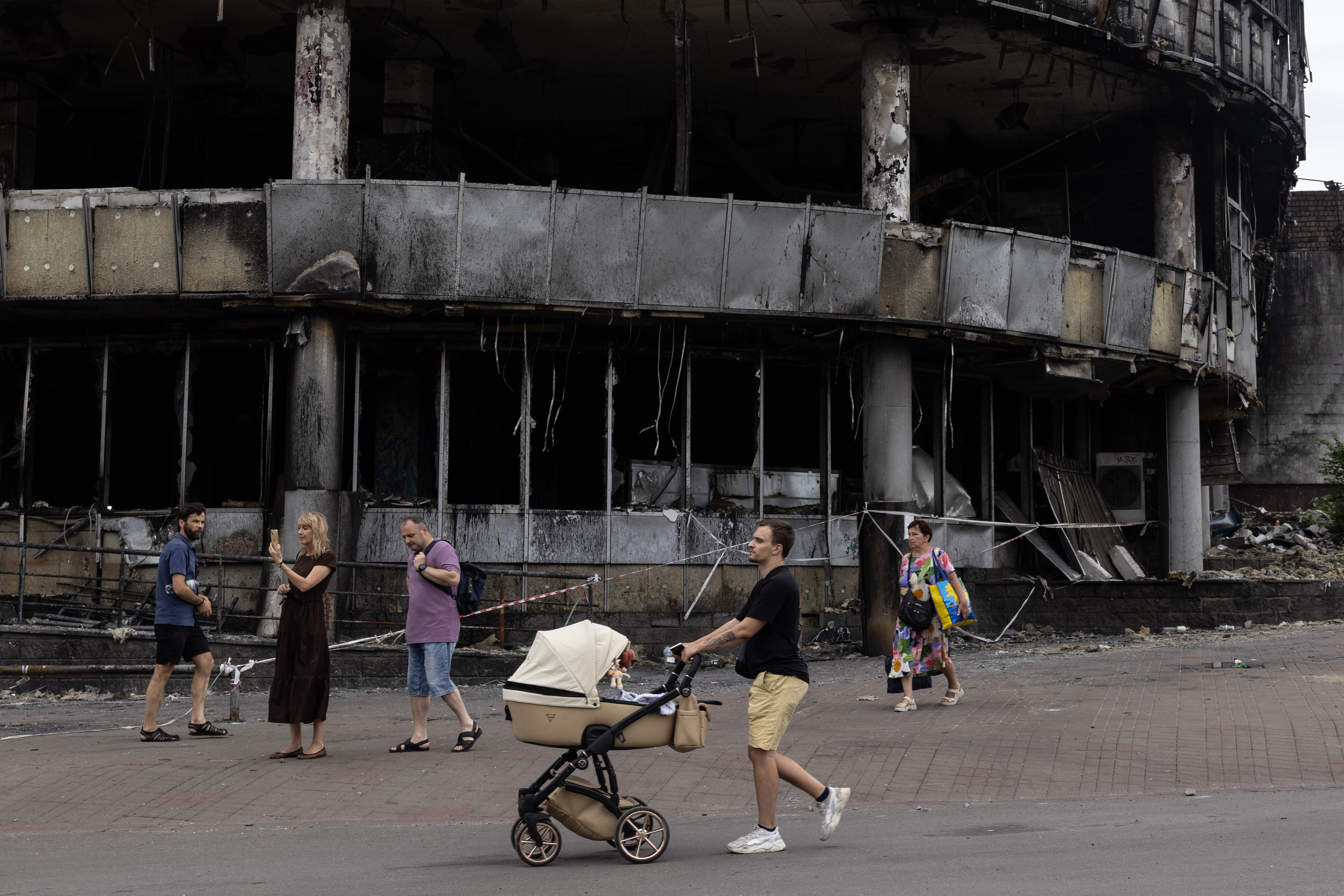 KYIV, UKRAINE - JULY 19: People walk by a burned building in the Lukyanivka area where attacks have destroyed multiple buildings after a large-scale attack overnight that left at least one person dead and thirteen injured on July 19, 2026 in Kyiv, Ukraine. Kyiv was hit with about 40 Iskander-M and hypersonic Zircon missiles. (Photo by Paula Bronstein/Getty Images)