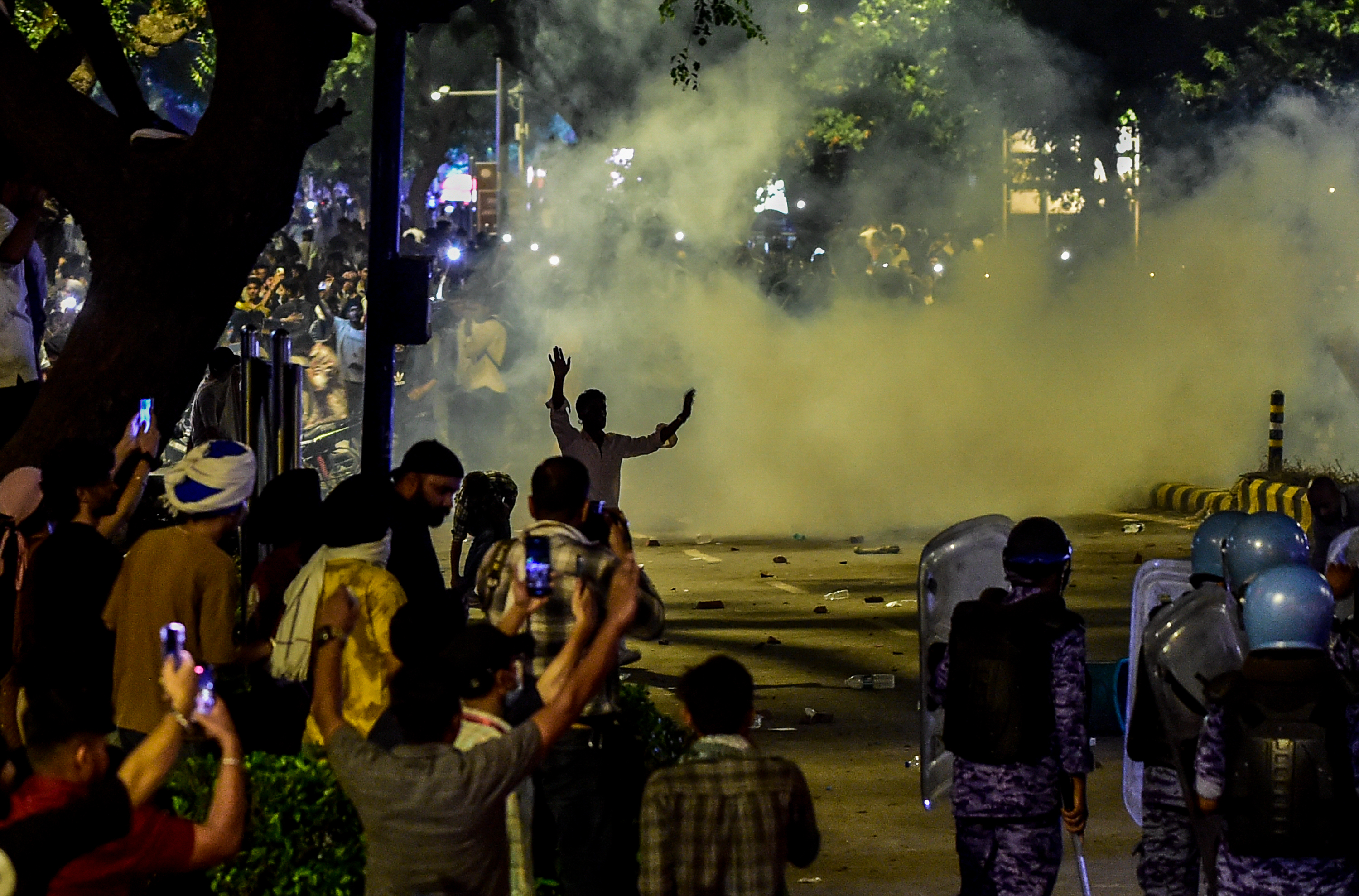NEW DELHI, INDIA - JULY 22: Tear gas fills the air as police officers in riot gear face protesters during a demonstration led by the Cockroach Janta Party (CJP) near Parliament Street in on July 22, 2026 in New Delhi, India. Protesters are demanding reforms to the country's education system and the resignation of India's education minister as protests continue into the week. Opposition leader Rahul Gandhi was detained on Tuesday and Sonam Wangchuk, an activist who was fasting in protest, was forcibly taken to hospital on Sunday. (Photo by Ritesh Shukla/Getty Images)
