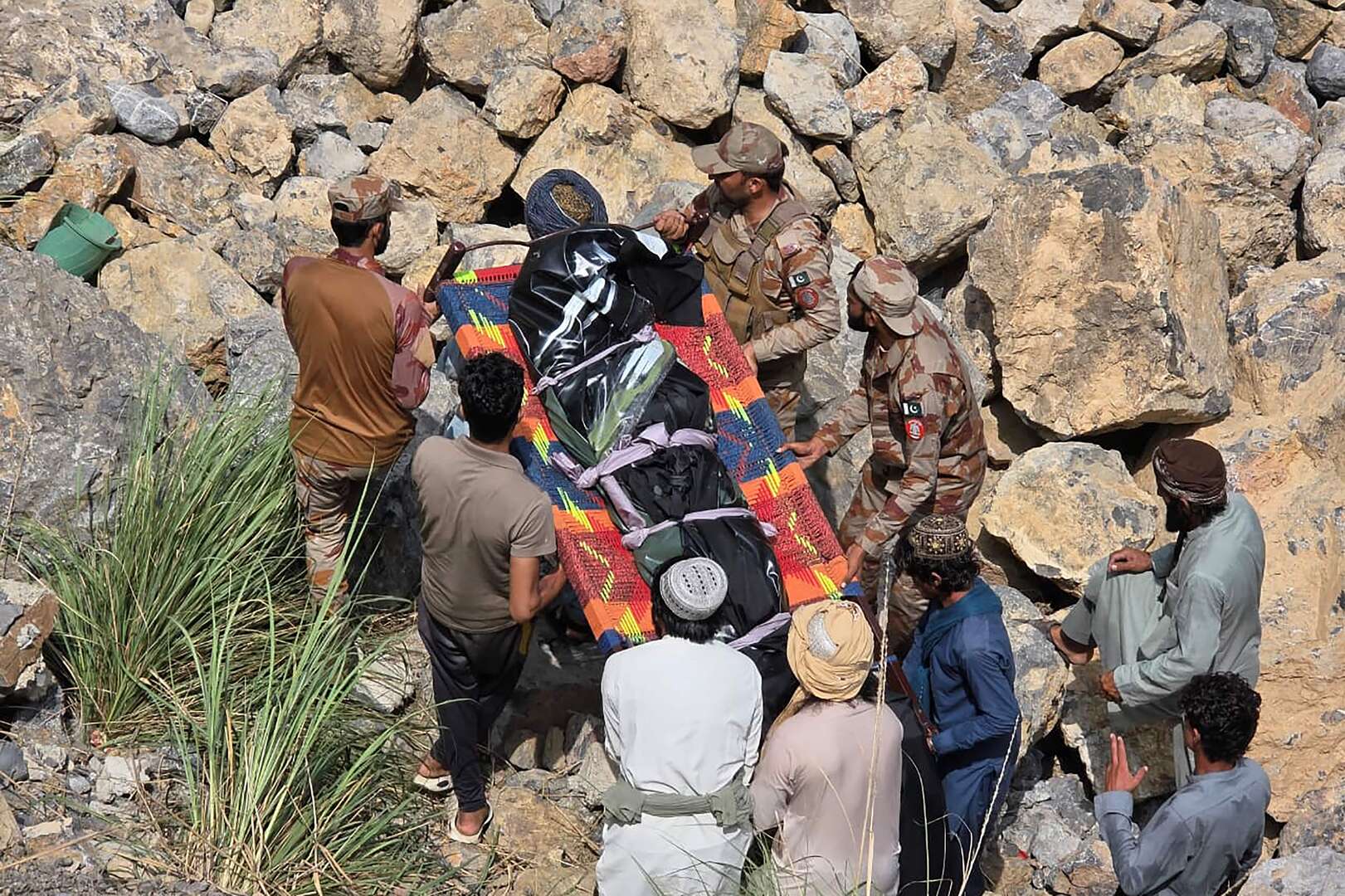 Frontier Corps personnel carry a dead body at the crash site of a passenger bus, in the mountainous Dana Sar area of Zhob district on July 3, 2026. An overloaded bus veered off a road and fell more than 20 metres into a ravine in western Pakistan on July 3, killing at least 40 people, officials said. [AFP]