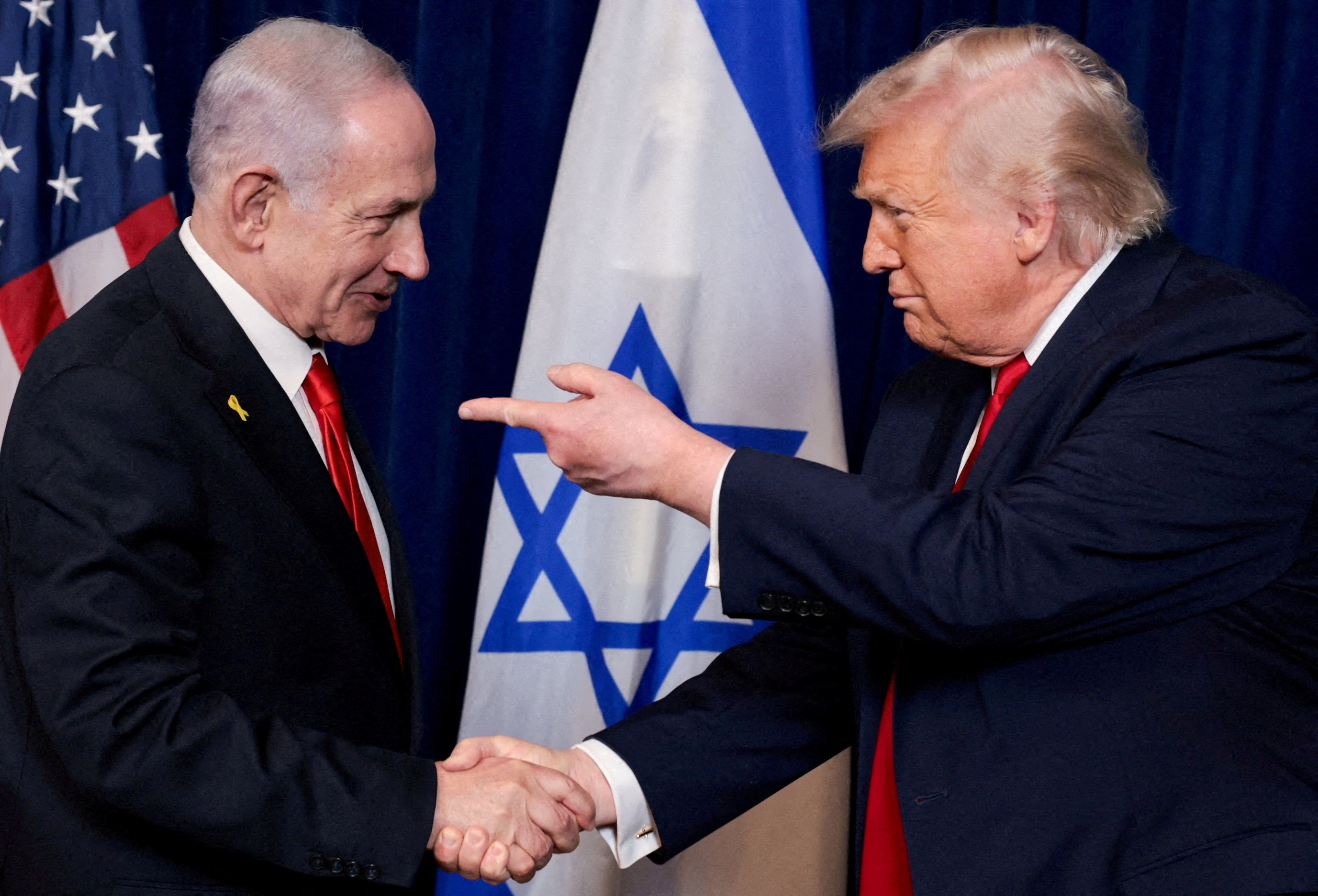 FILE PHOTO: U.S. President Donald Trump points his finger towards Israeli Prime Minister Benjamin Netanyahu as they shake hands during a press conference after meeting at Trump’s Mar-a-Lago club in Palm Beach, Florida, U.S., December 29, 2025. REUTERS/Jonathan Ernst/File Photo