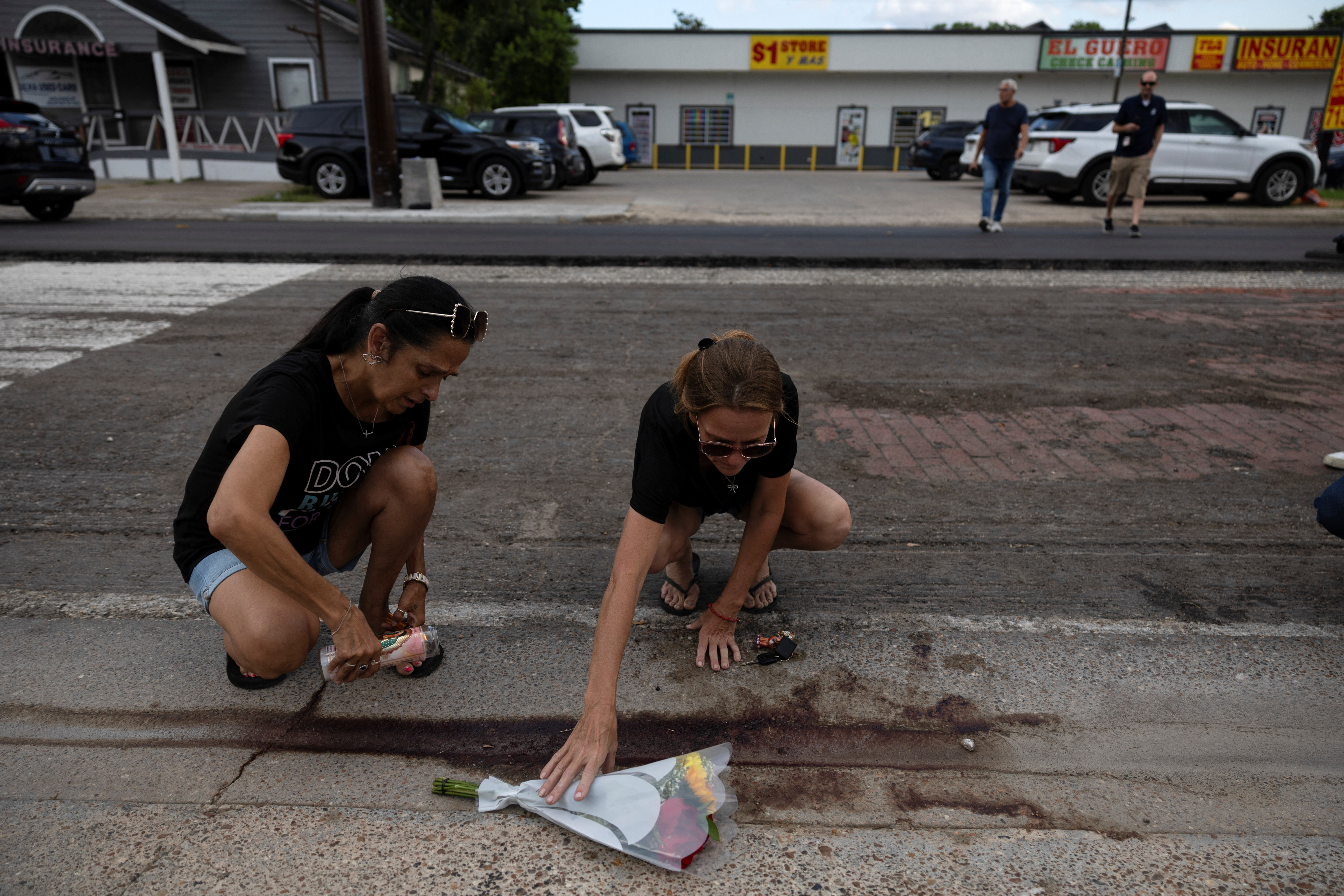Gina Danielsen and Ronda Smith place a candle next to flowers, next to the scene where an ICE agent fatally shot a Mexican motorist, identified as Lorenzo Salgado Araujo, during a vehicle stop in Houston, Texas, U.S., July 7, 2026. REUTERS/Antranik Tavitian