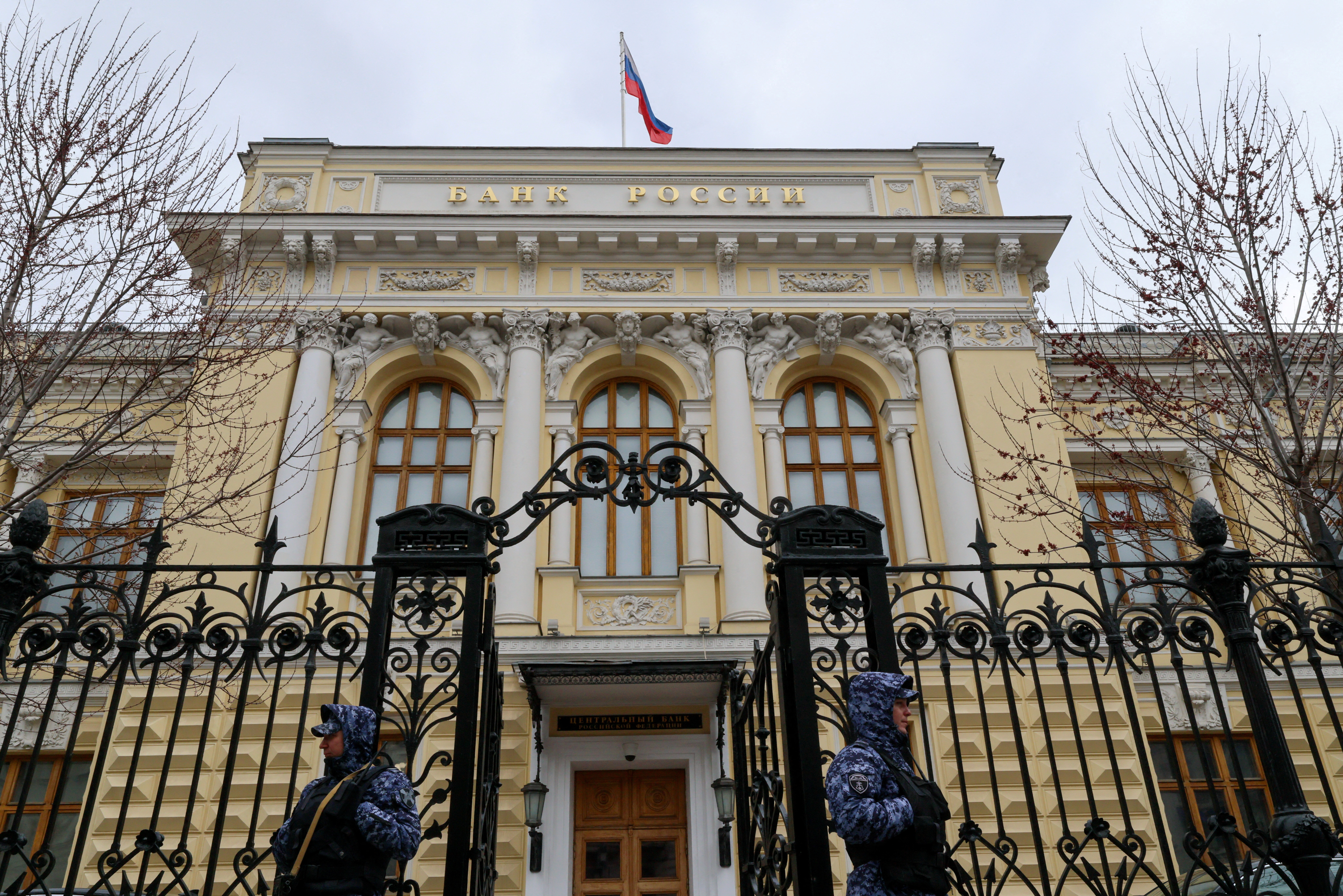 Uniformed Russian National Guard officers stand in a line outside the columned facade of the Central Bank building in Moscow