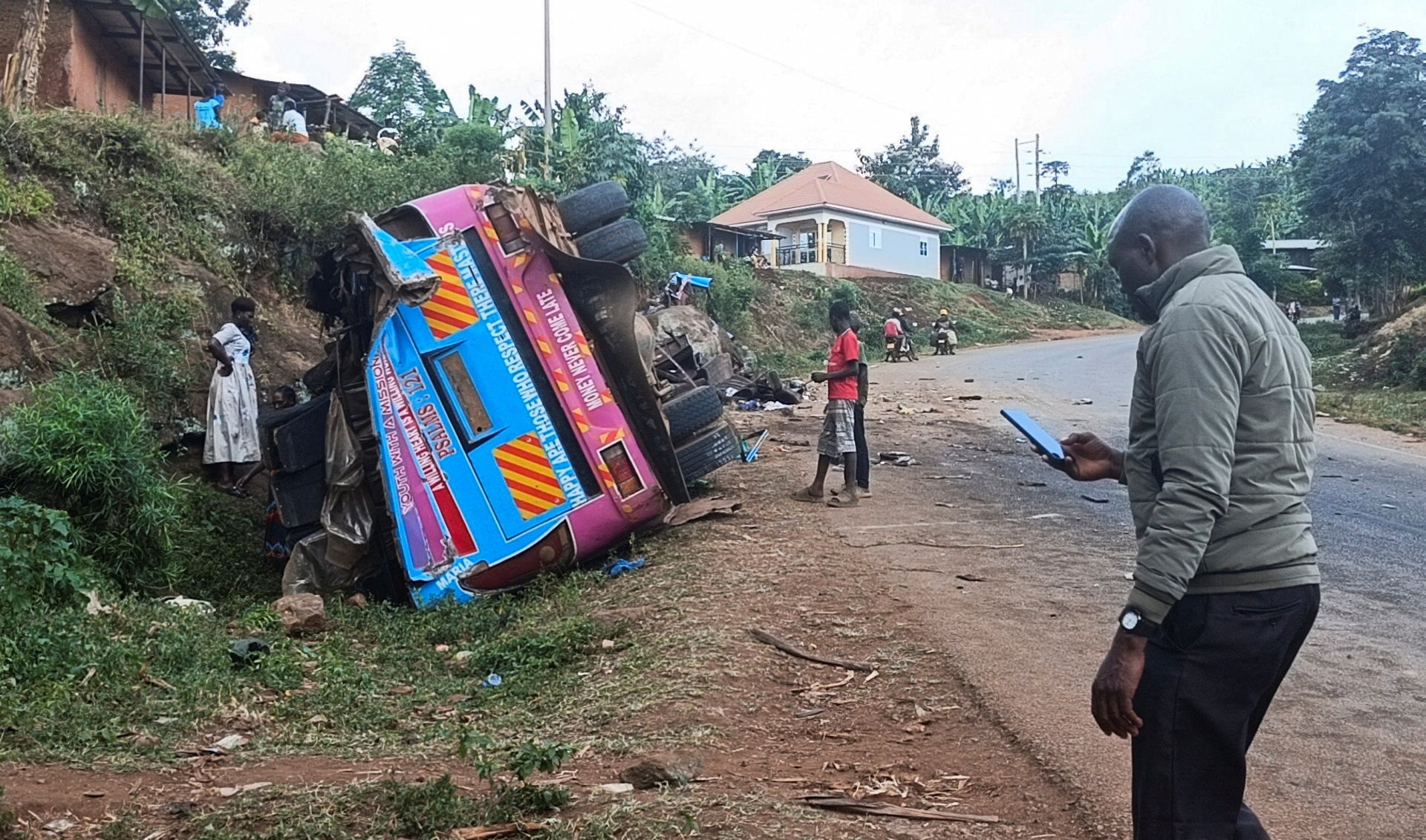 People stand near the wreckage of a bus.
