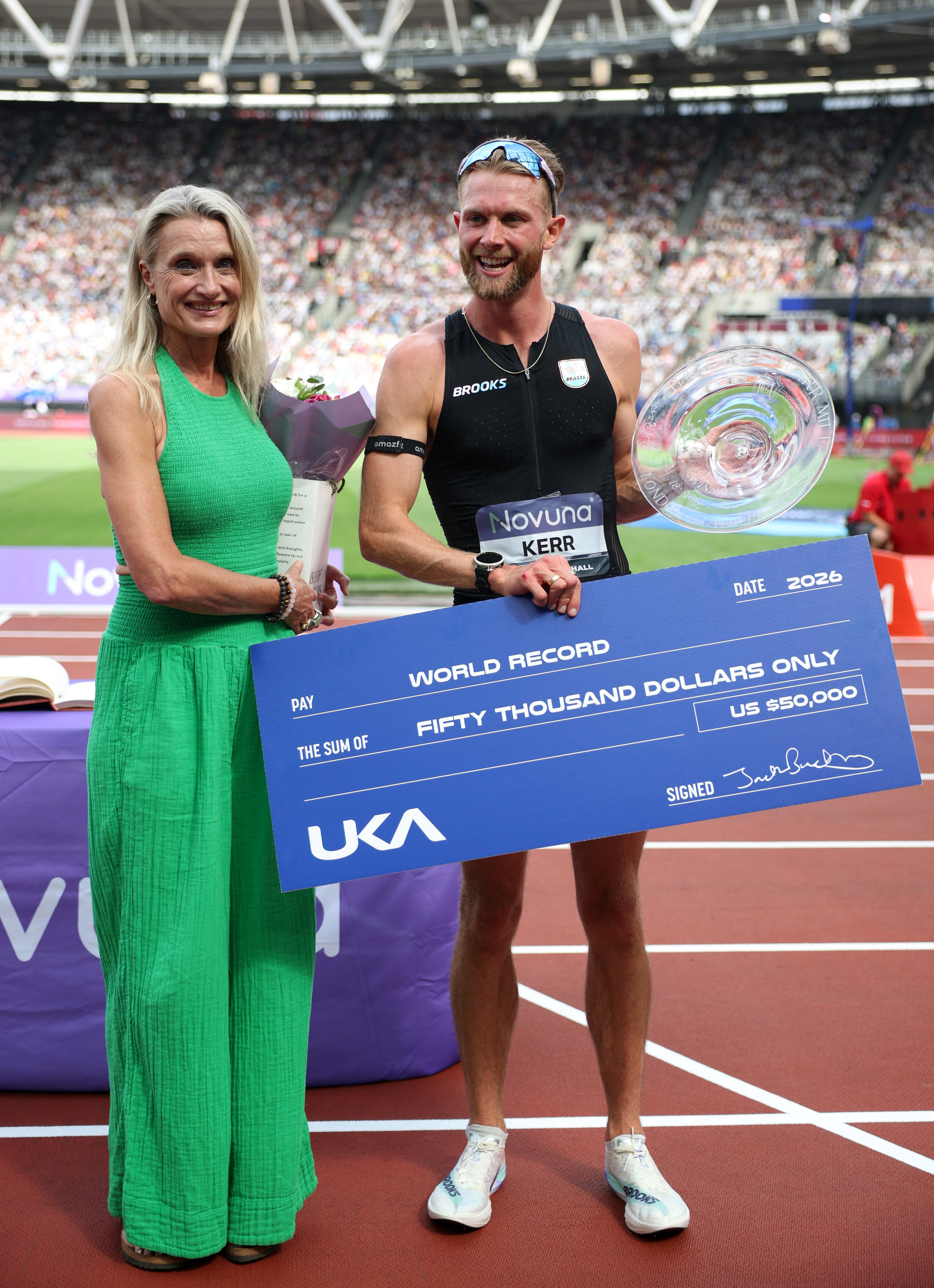 Athletics - Diamond League - London - London Stadium, London, Britain - July 18, 2026 Britain's Josh Kerr receives a giant cheque for breaking the World Record in the men's 1 mile final REUTERS/Isabel Infantes
