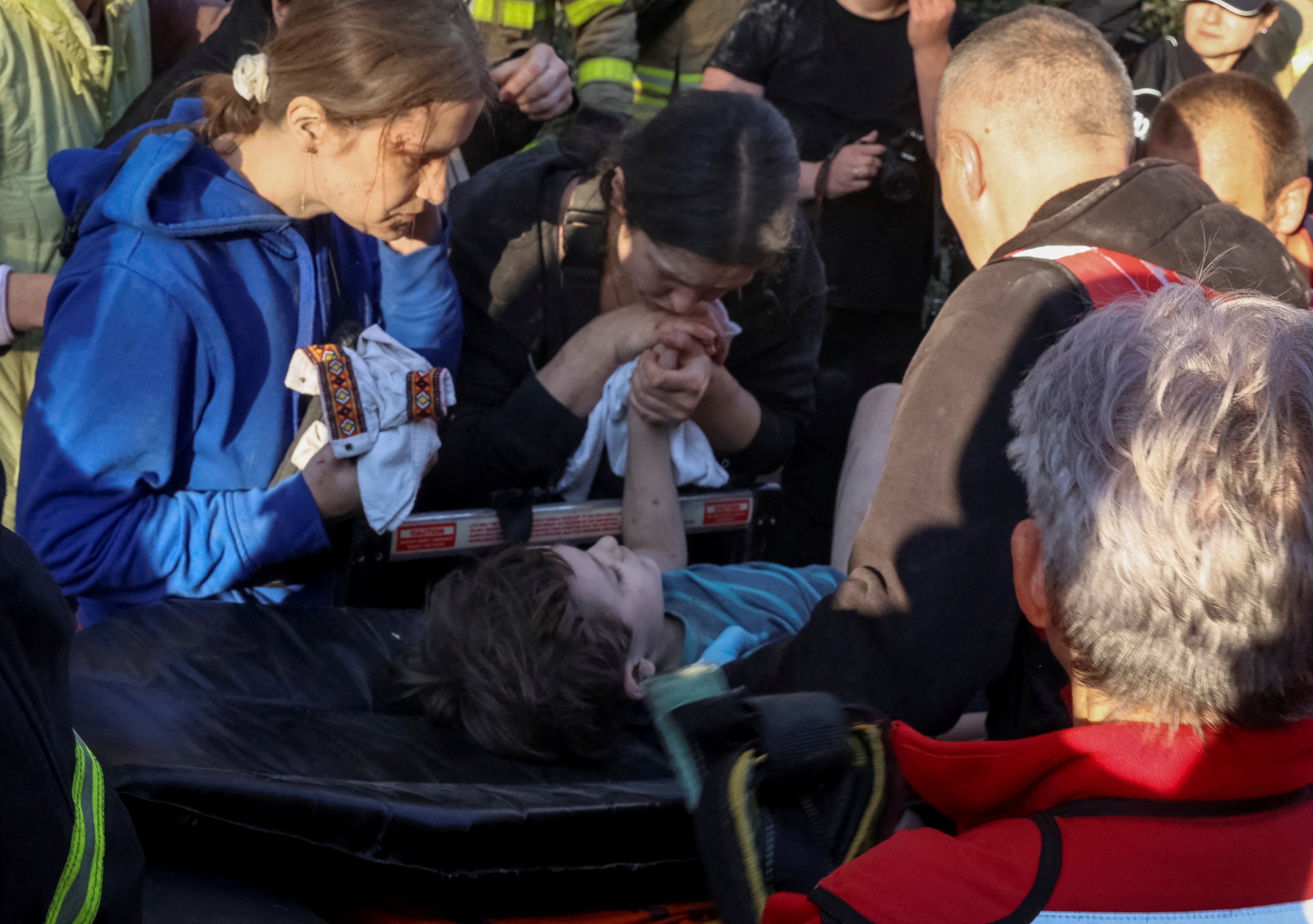 A woman holds the hand of an injured child as medical workers evacuate him at the site of an apartment building hit by a Russian missile strike, amid Russia's attack on Ukraine, in Lviv, Ukraine July 30, 2026. REUTERS/Roman Baluk TPX IMAGES OF THE DAY