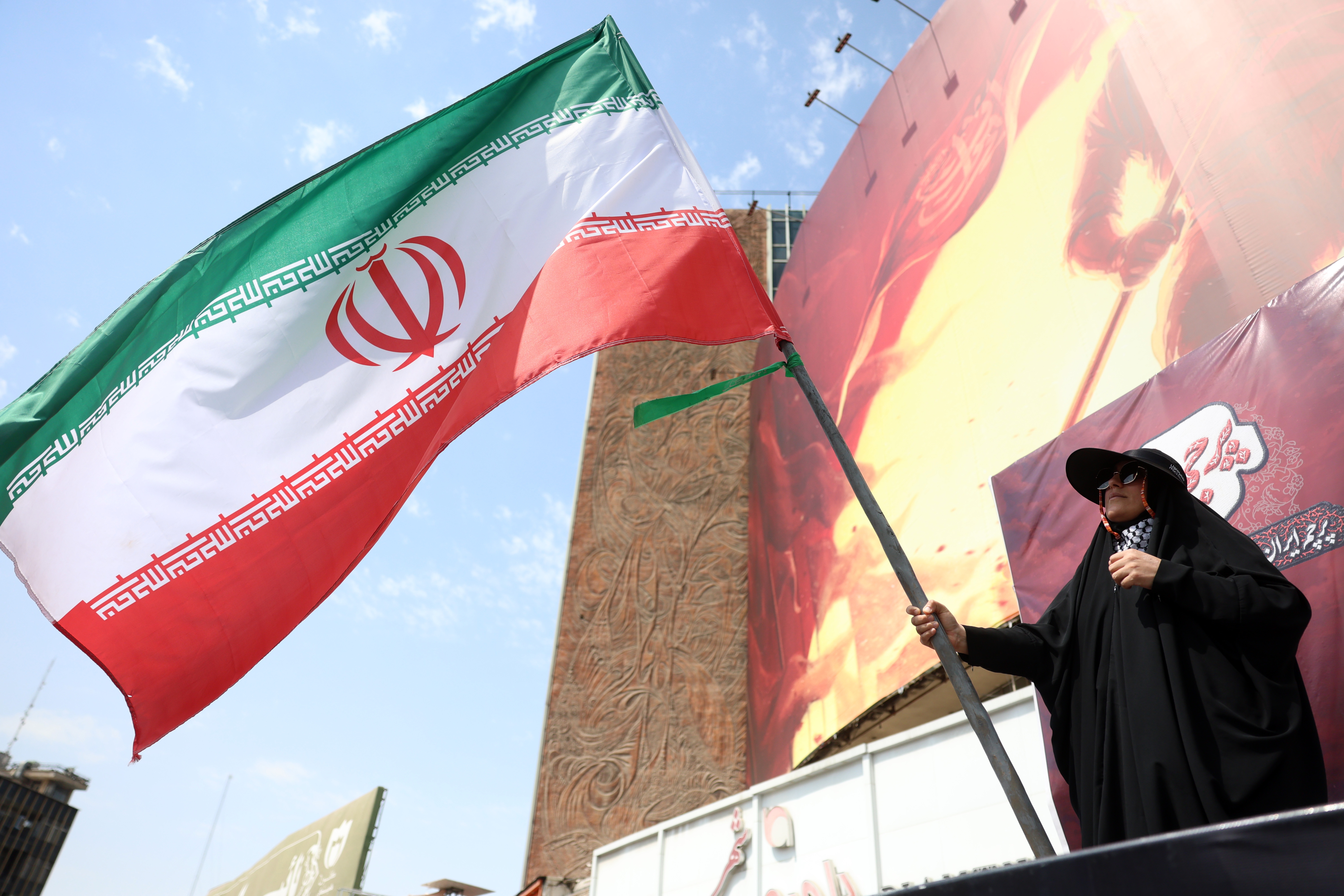 Iranian woman flies Iran's national flag at the Valiasr square