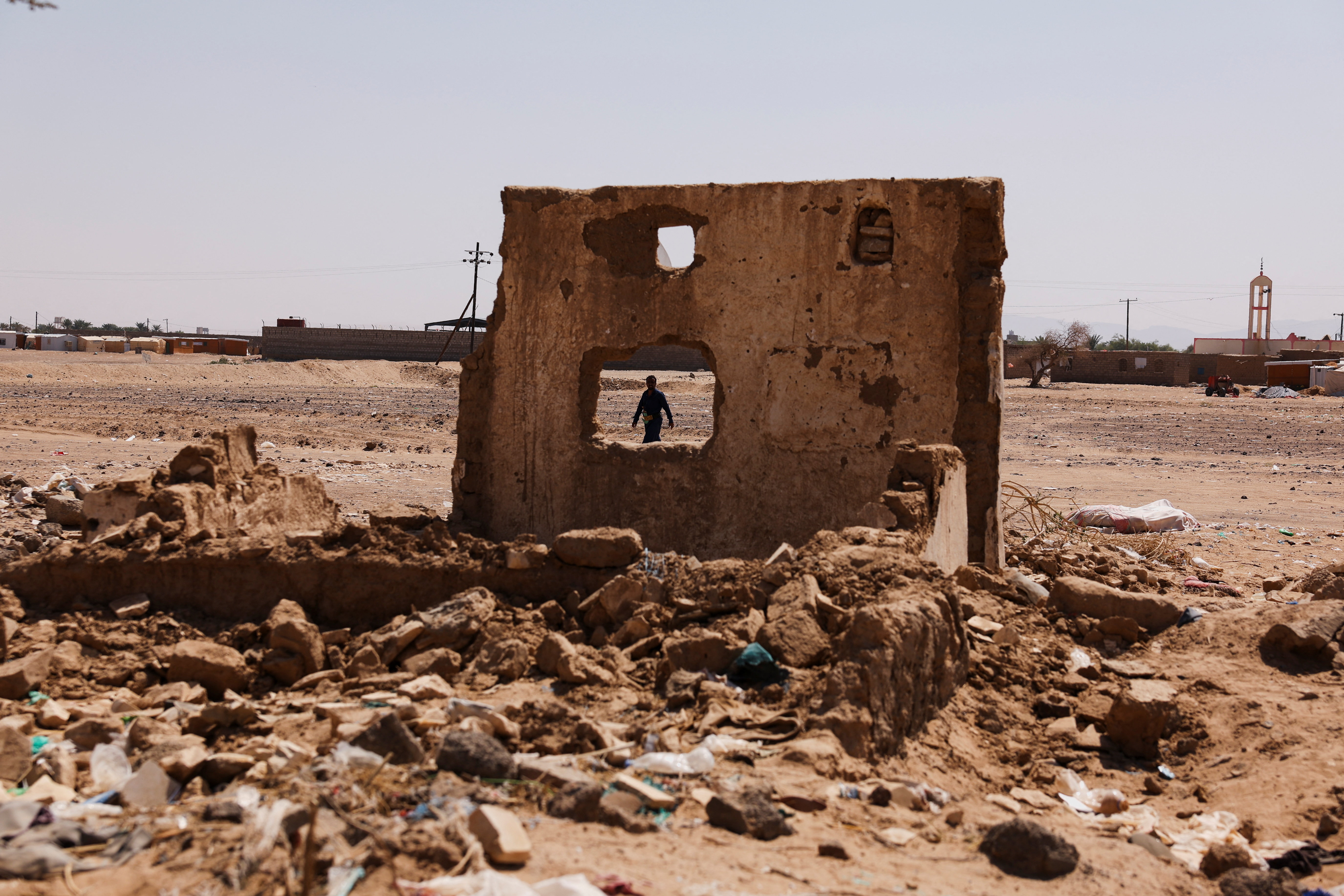 : A man walks past a damaged building in an internally displaced persons (IDP) camp in Marib, Yemen, November 3, 2024.
