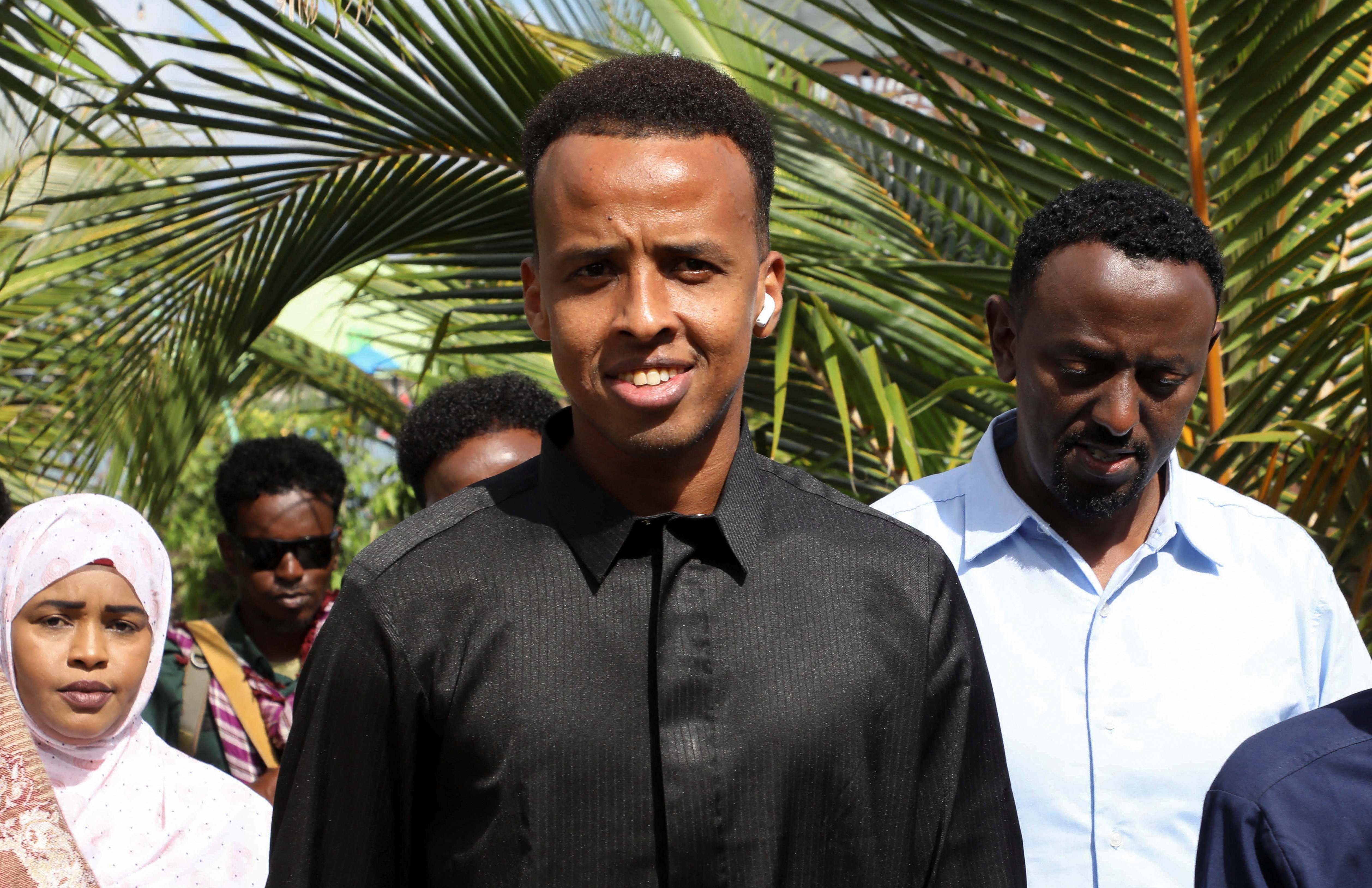 Somali referee Omar Abdulkadir Artan stands beside other people.