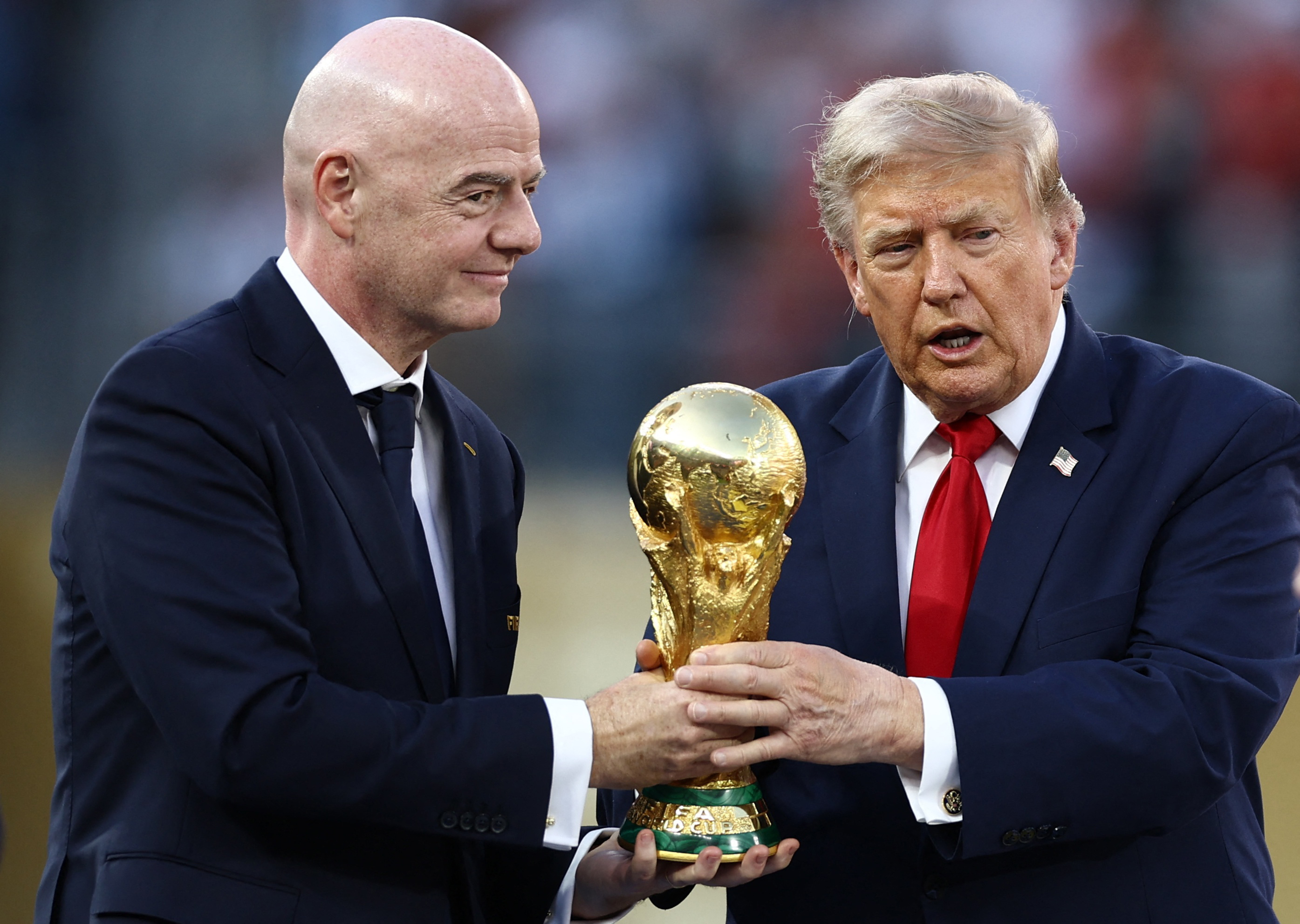 Two men hold the World Cup trophy