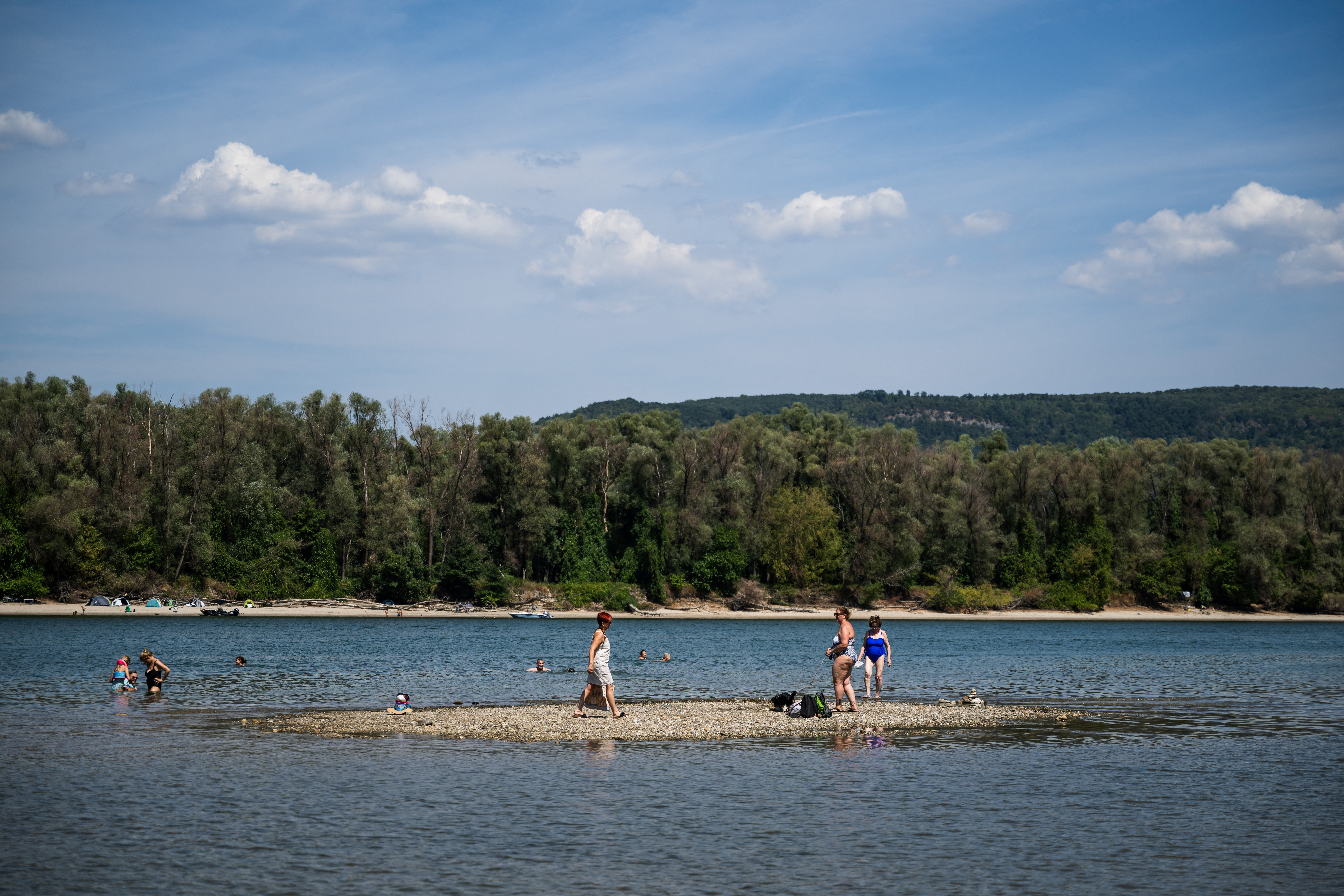 People spend time on a newly exposed island due to the low water level of the Danube River in Kisoroszi, Hungary, August 1, 2026. REUTERS/Marton Monus