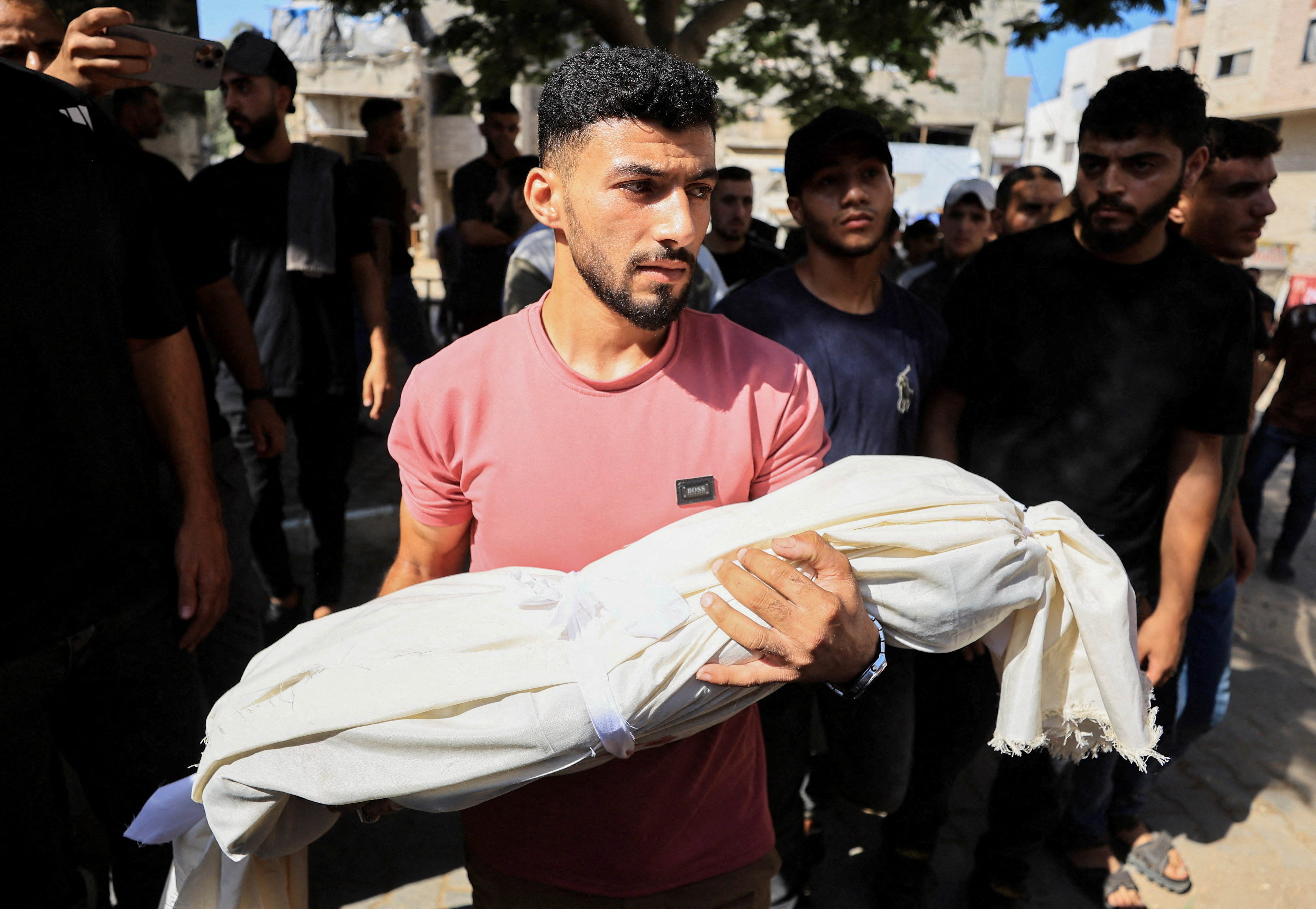 A mourner carries the body of a Palestinian child who was killed
