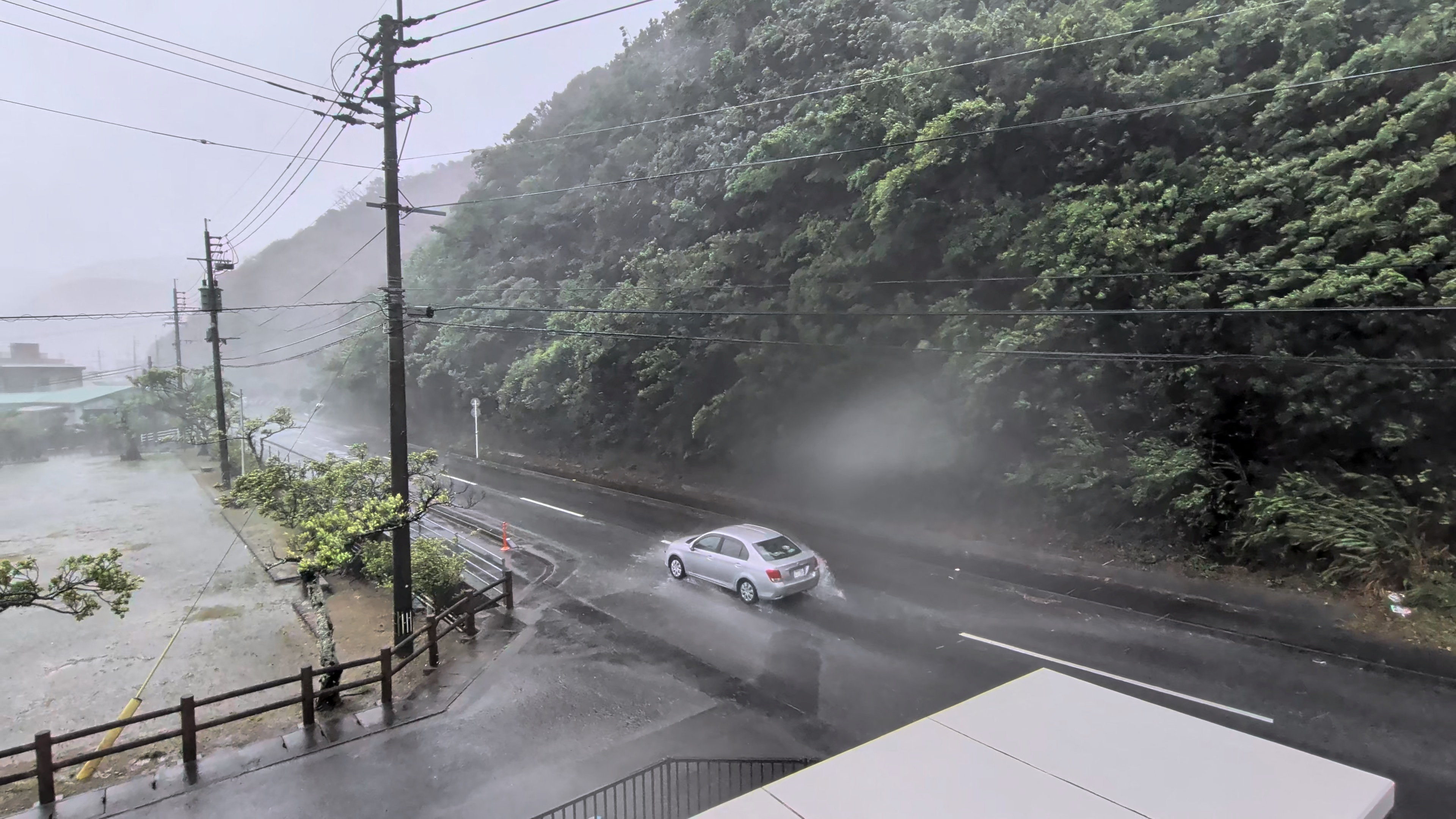 A car makes its way through strong winds and rain.
