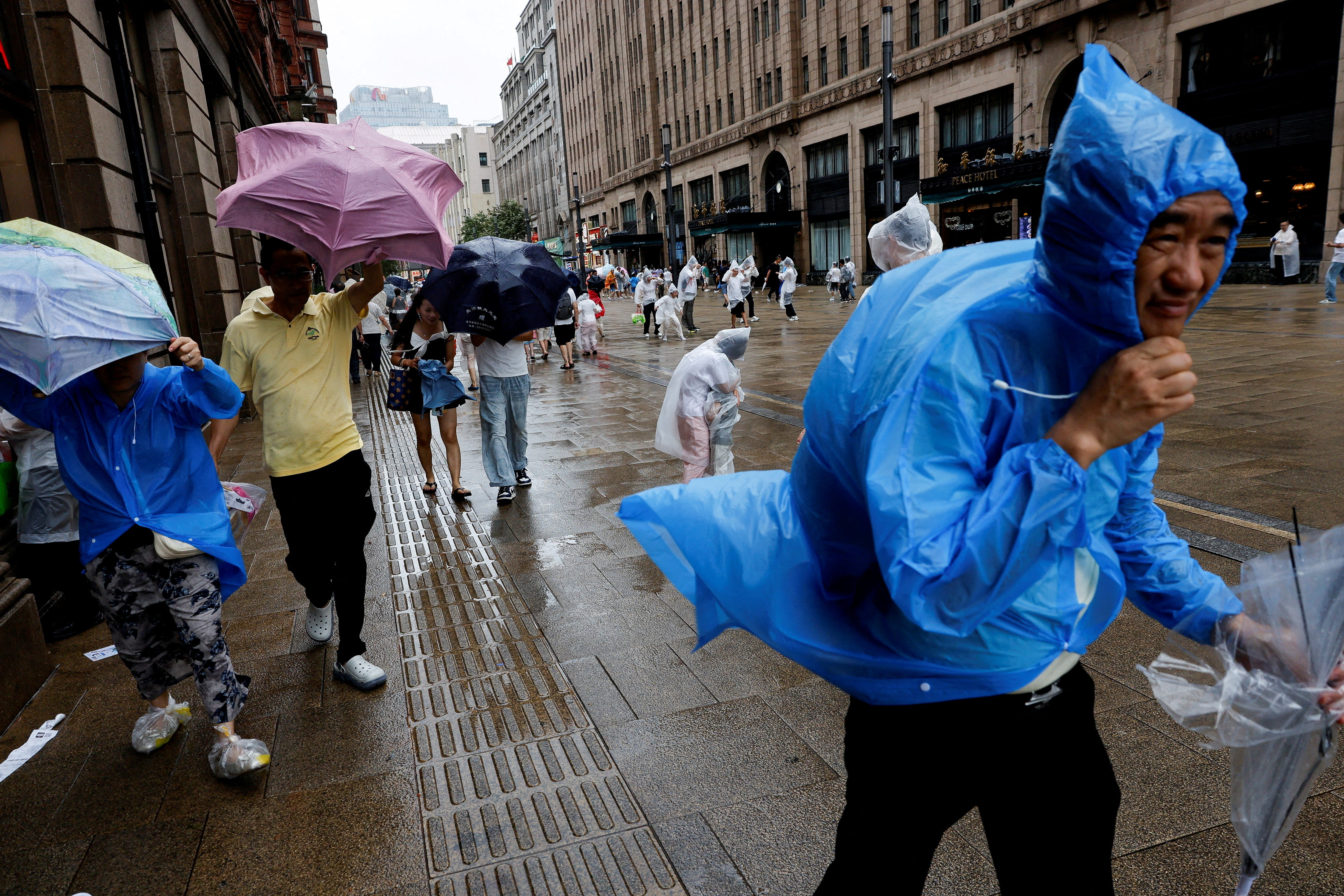 People use umbrellas and raincoats as winds intensify ahead of the arrival of Typhoon Dolphin in Shanghai