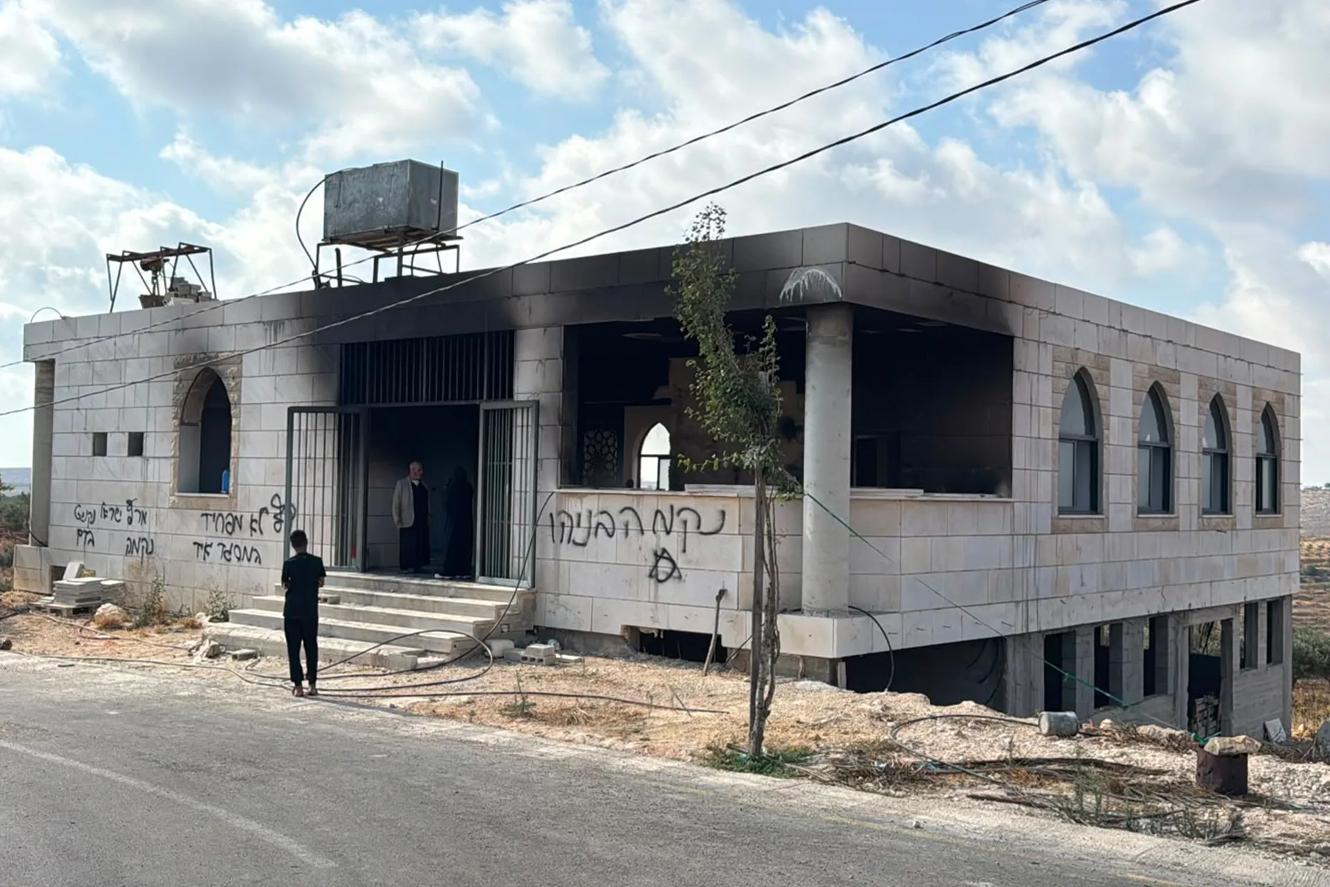 Hebrew graffiti covers the walls of a burned mosque in the town of Qusra, south of Nablus. According to locals, the slogans include explicit threats such as ‘Death to Arabs’ and ‘We came for revenge’ [Al Jazeera]