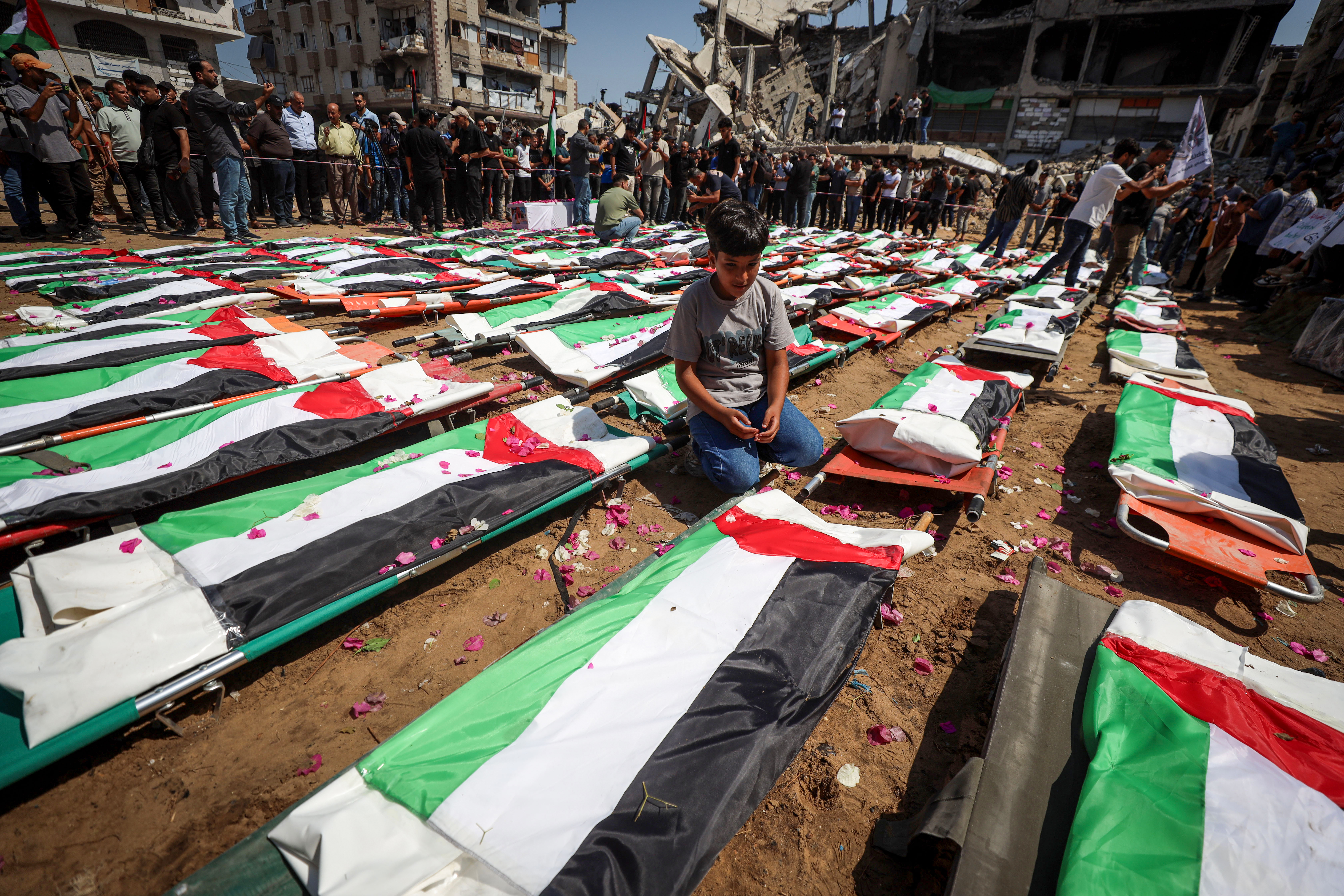 Child cries beside a body bag during the funeral ceremony