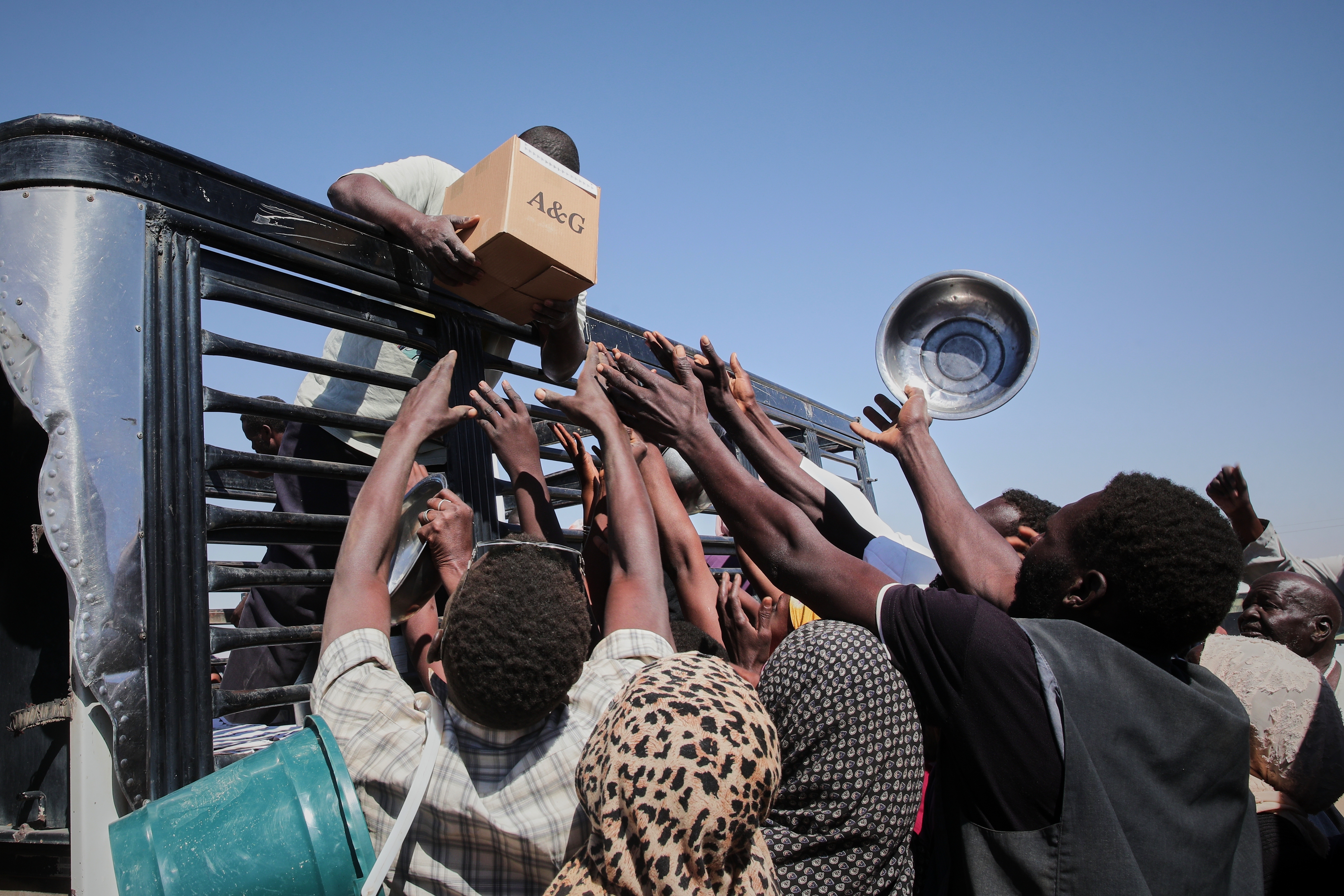 FILE.- Sudanese families displaced from El-Fasher reach out as aid workers distribute food supplies at the newly established El-Afadh camp in Al Dabbah, in Sudan's Northern State, Nov. 16, 2025. (AP Photo/Marwan Ali,File)