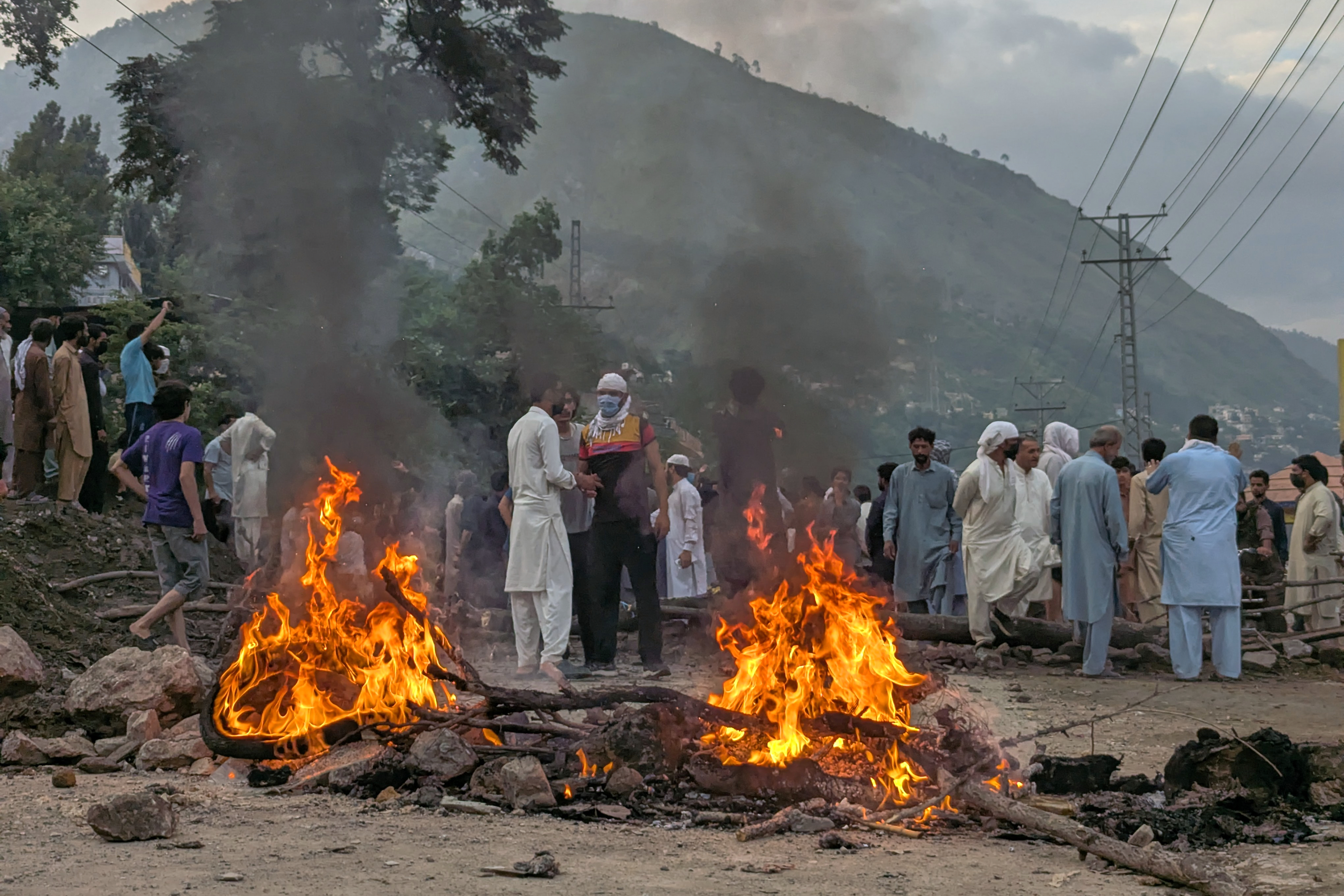 Supporters of an outlawed alliance of activist groups "Joint Awami Action Committee" (JAAC) block a road and set on fire woods after clashes with police during protest demanding greater political rights and the abolition of 12 legislative refugee seats, in Muzaffarabad, the capital of Pakistan-administered Kashmir, Friday, July 31, 2026. (AP Photo/Ishfaq Hussain)