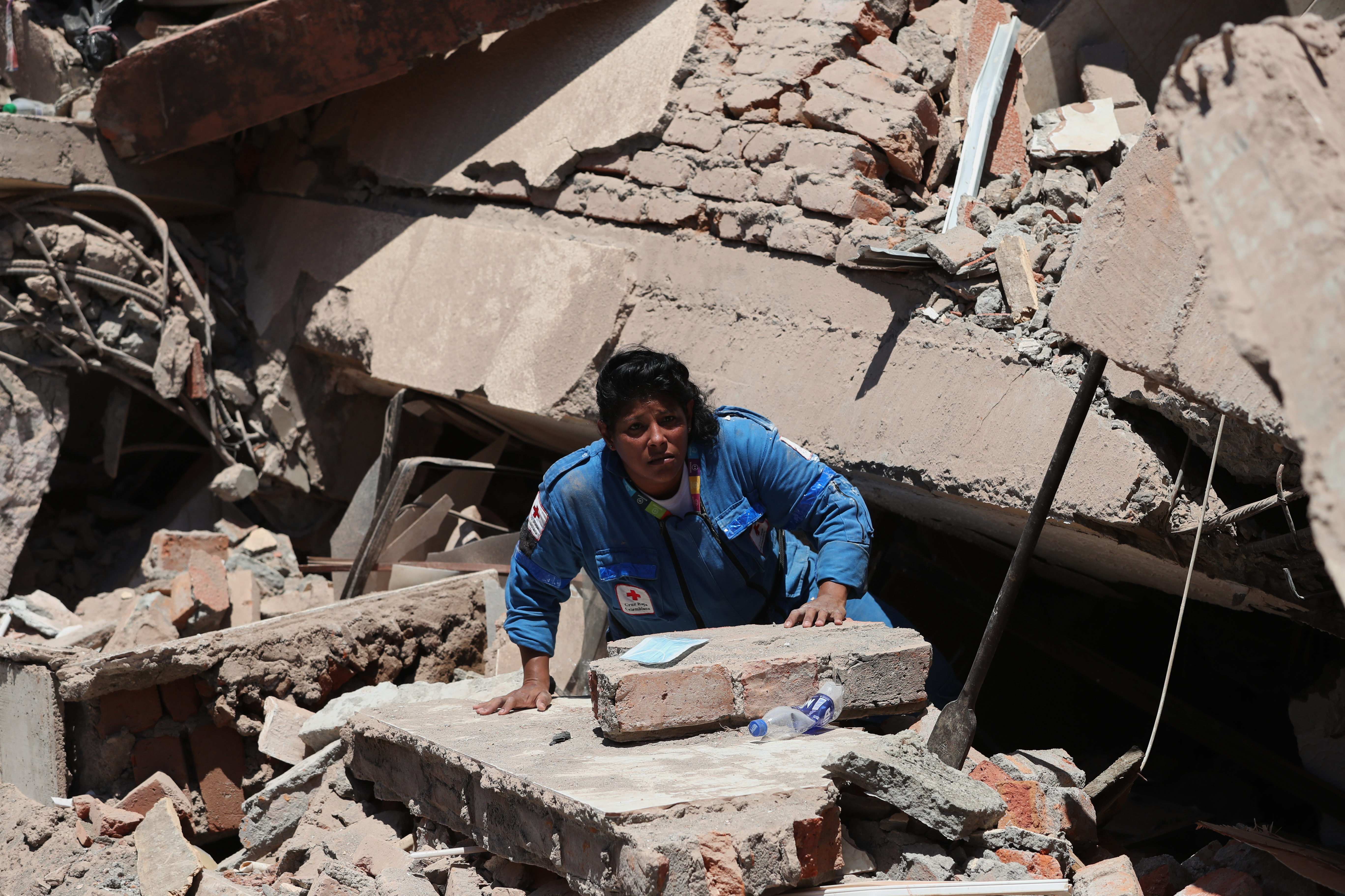 A rescue worker searches for survivors in the rubble of buildings.